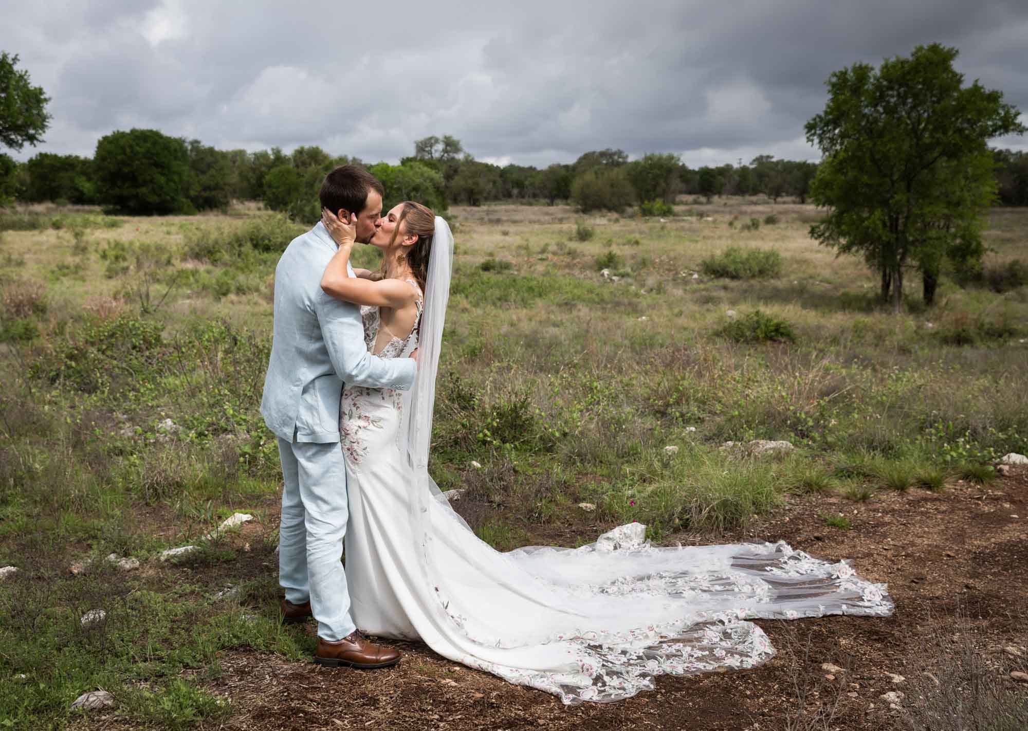 Lady Bird Johnson Wildflower Center wedding photos of a bride and groom kissing in middle of Savanna Meadow