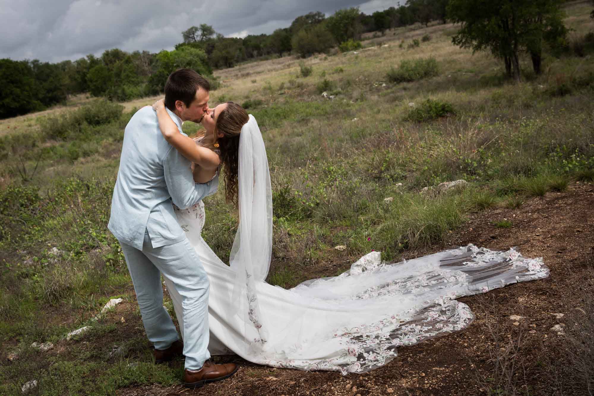 Lady Bird Johnson Wildflower Center wedding photos of a bride and groom kissing in middle of Savanna Meadow