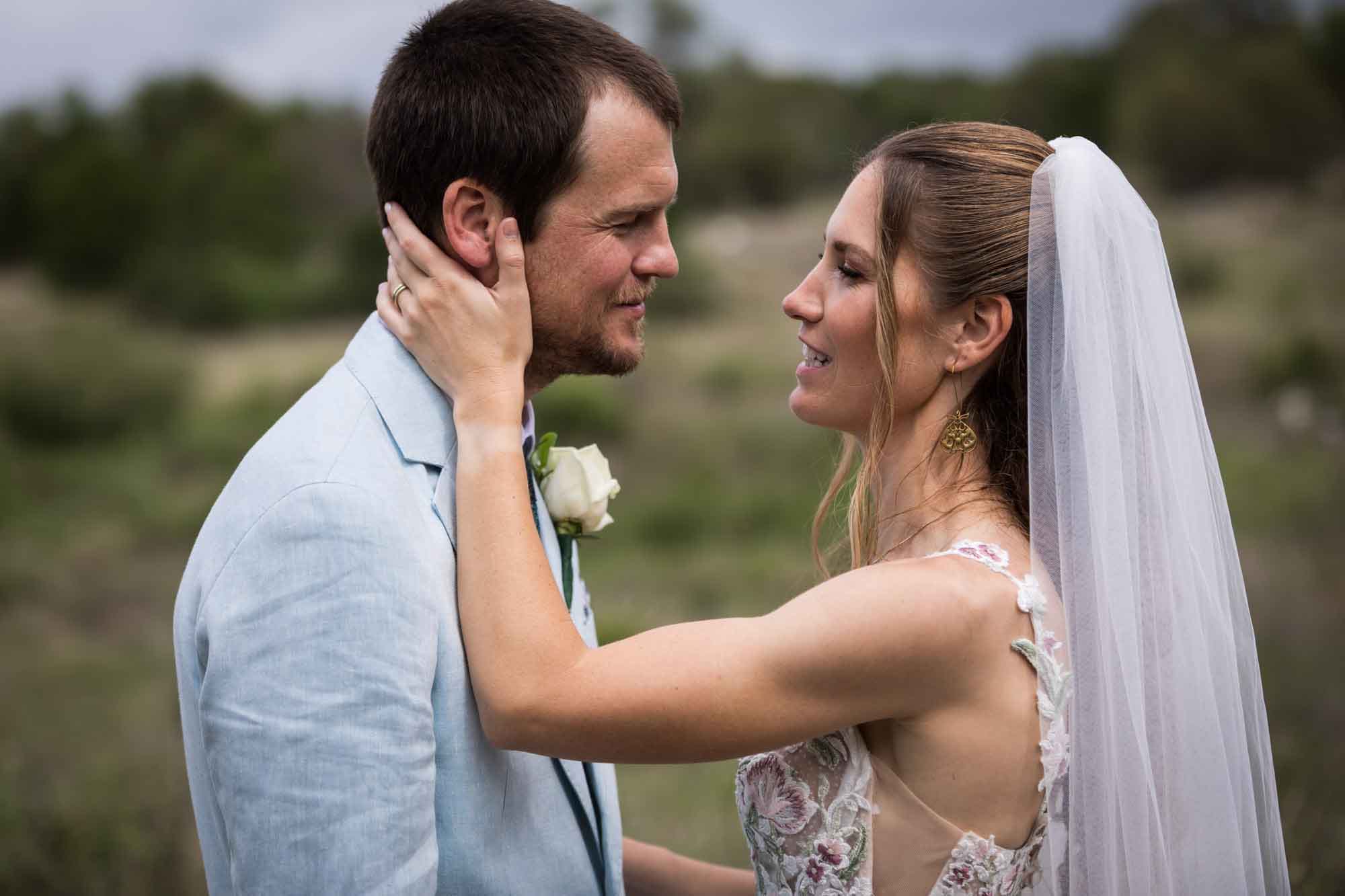 Lady Bird Johnson Wildflower Center wedding photos of a bride with hand on groom's face in middle of Savanna Meadow