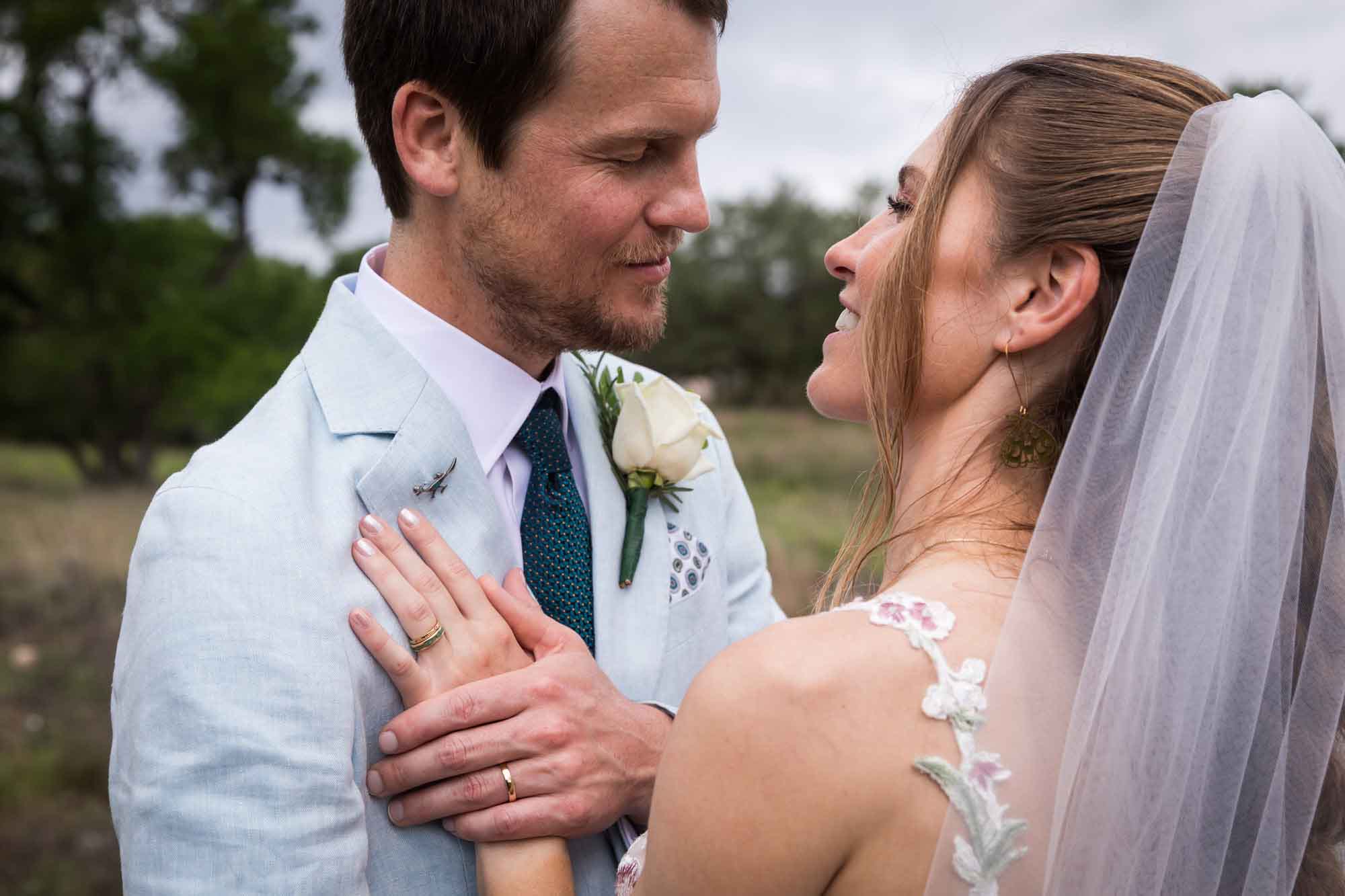 Lady Bird Johnson Wildflower Center wedding photos of a groom holding bride's hand on his lapel in middle of Savanna Meadow