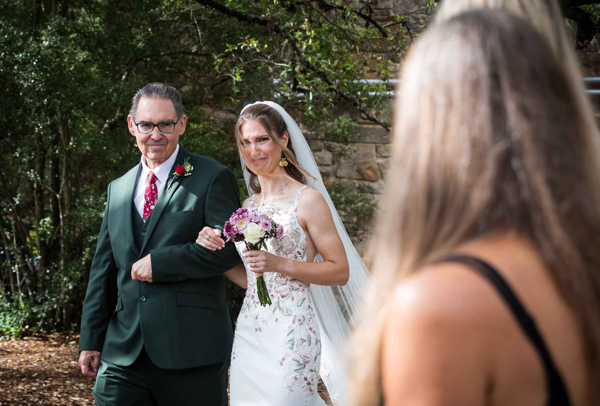 Bride holding father's arm stepping in front of guests as she walks down aisle during a Lady Bird Johnson Wildflower Center wedding