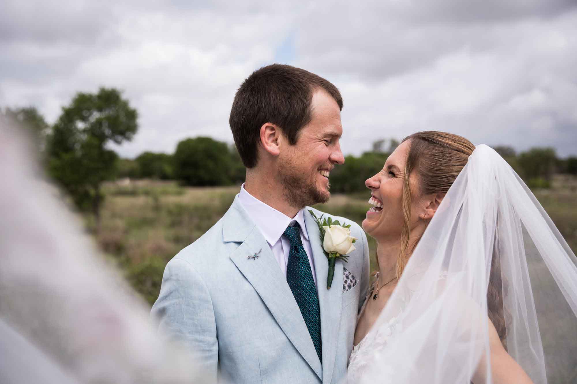 Lady Bird Johnson Wildflower Center wedding photos of a bride and groom hugging and laughing in middle of Savanna Meadow