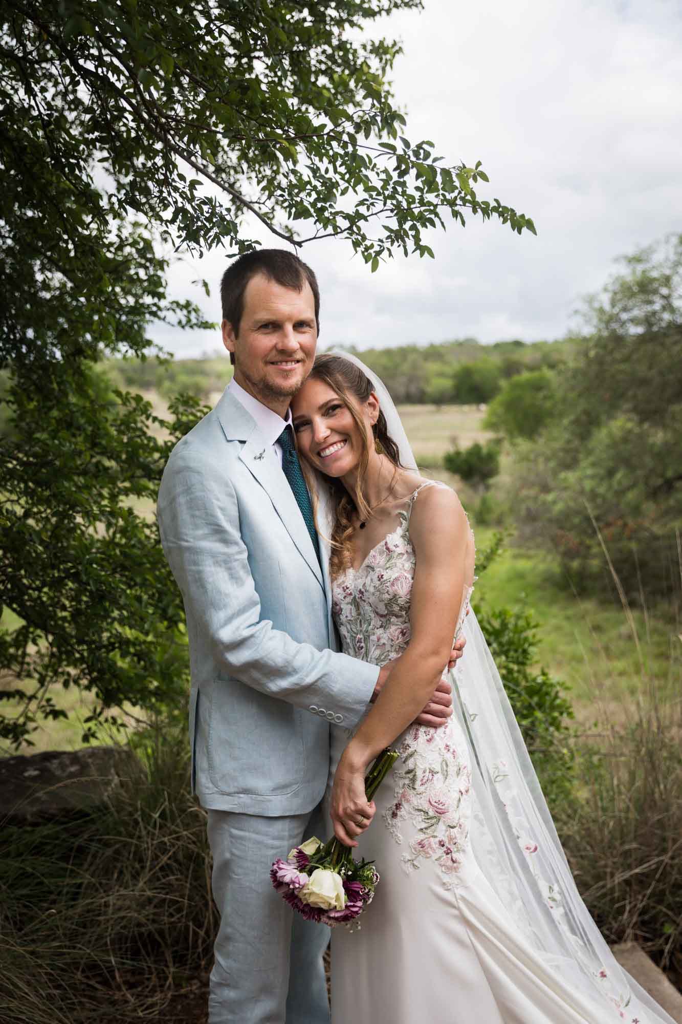 Lady Bird Johnson Wildflower Center wedding photos of a bride and groom hugging in front of Savanna Meadow