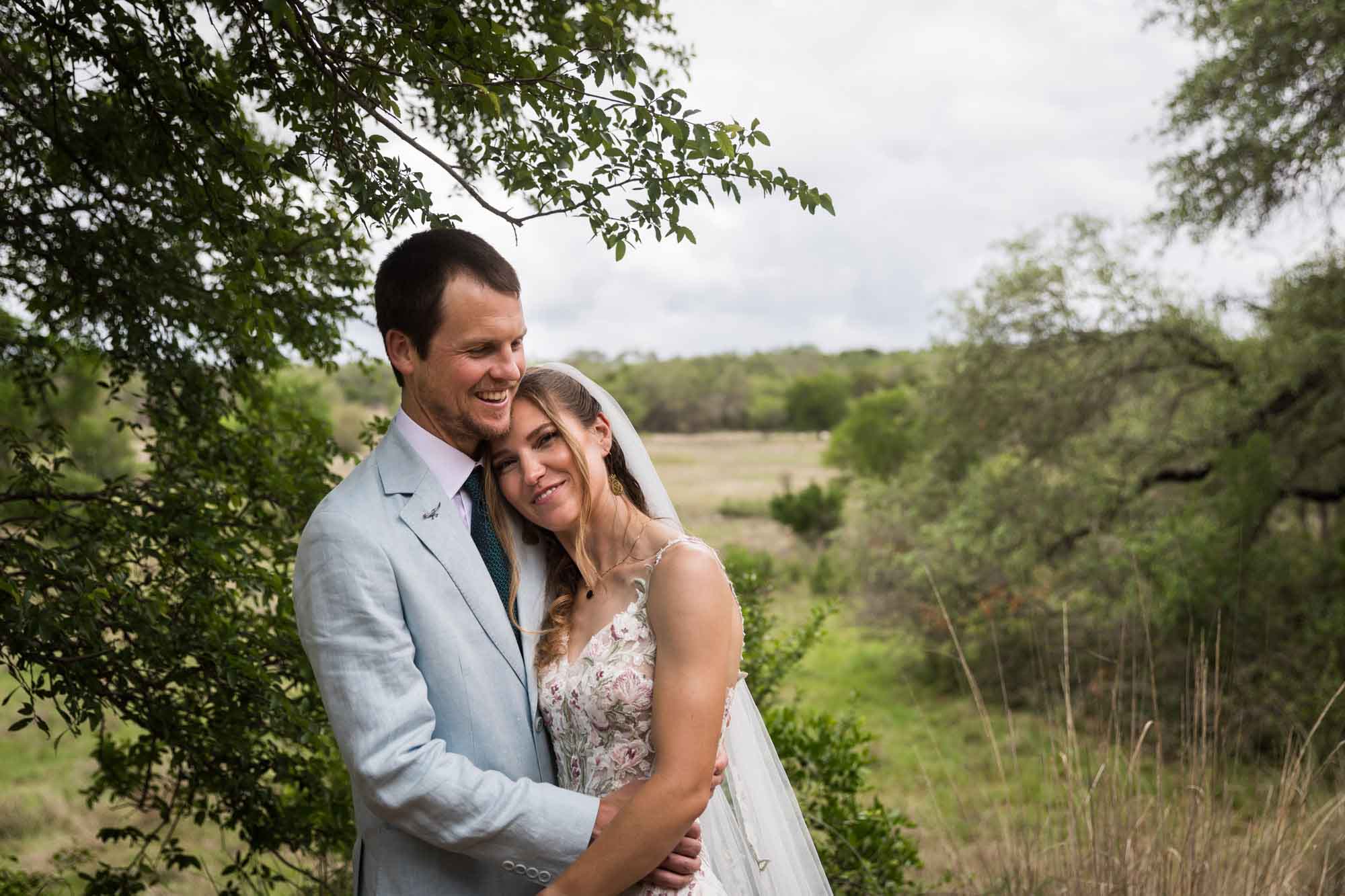 Lady Bird Johnson Wildflower Center wedding photos of a bride and groom hugging in front of Savanna Meadow