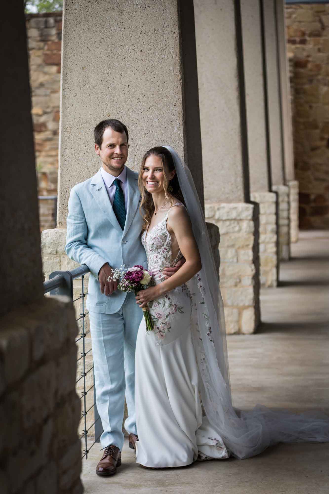 Lady Bird Johnson Wildflower Center wedding photos of a bride and groom standing in between limestone columns