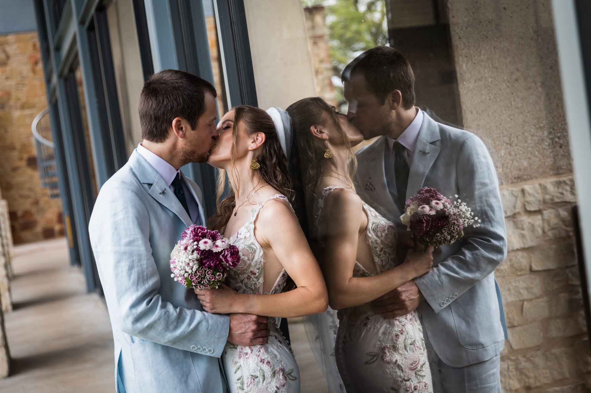 Lady Bird Johnson Wildflower Center wedding photos of a bride and groom kissing in front of reflective glass windows