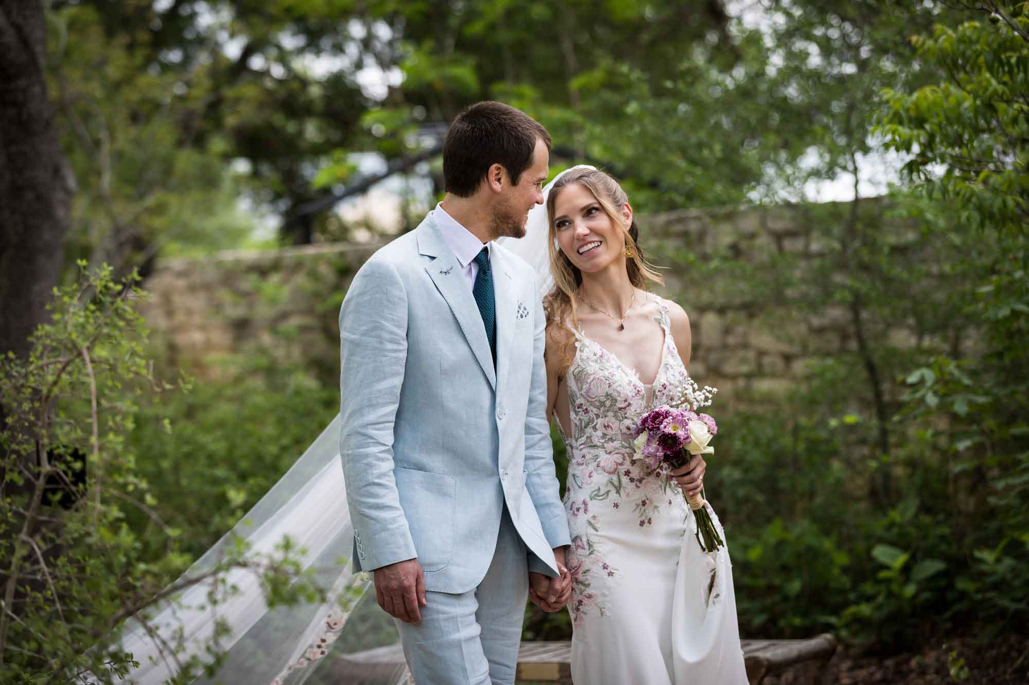 Lady Bird Johnson Wildflower Center wedding photos of a bride and groom walking hand in hand in woodland gardens