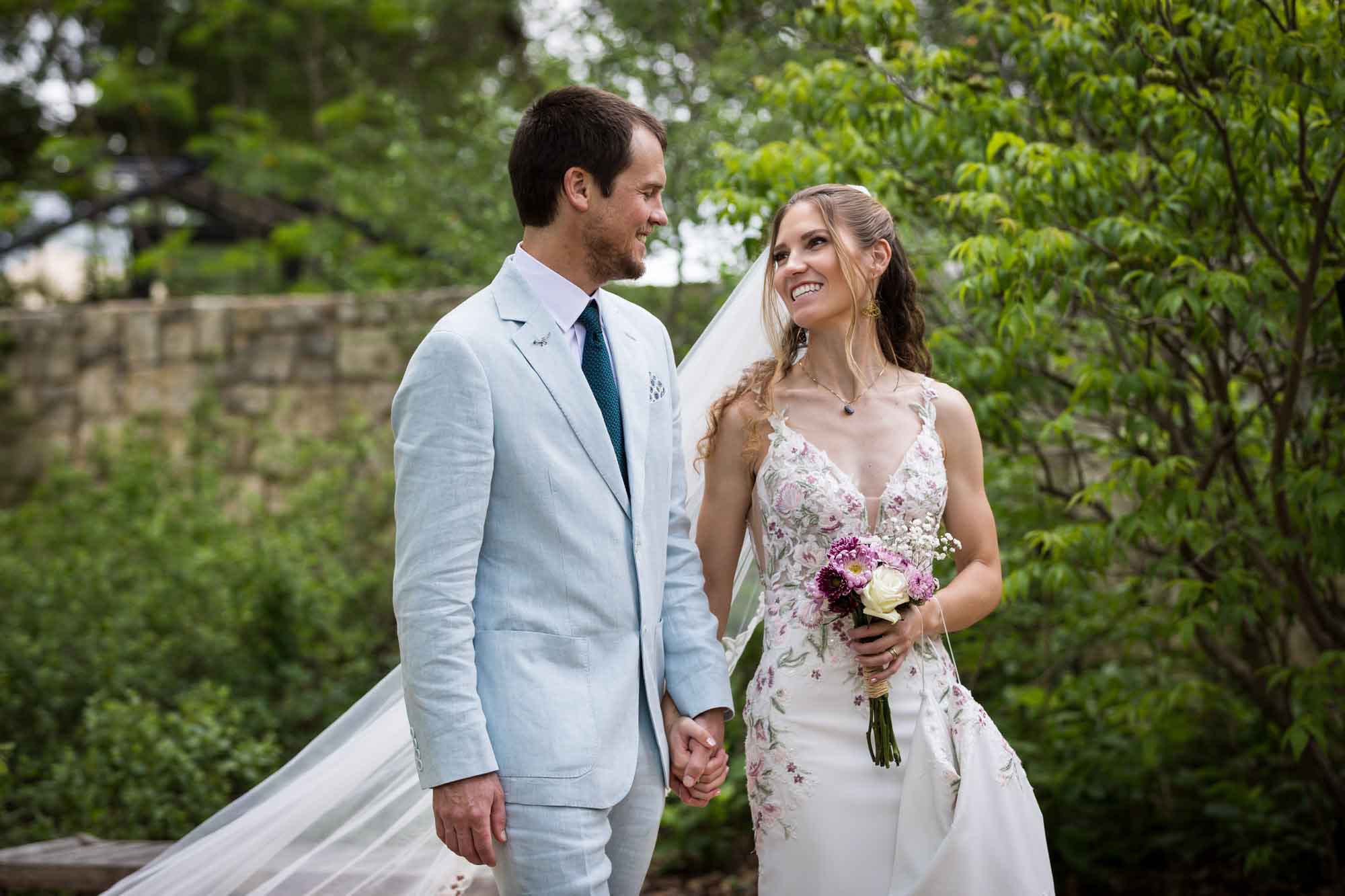 Lady Bird Johnson Wildflower Center wedding photos of a bride and groom walking hand in hand in woodland gardens