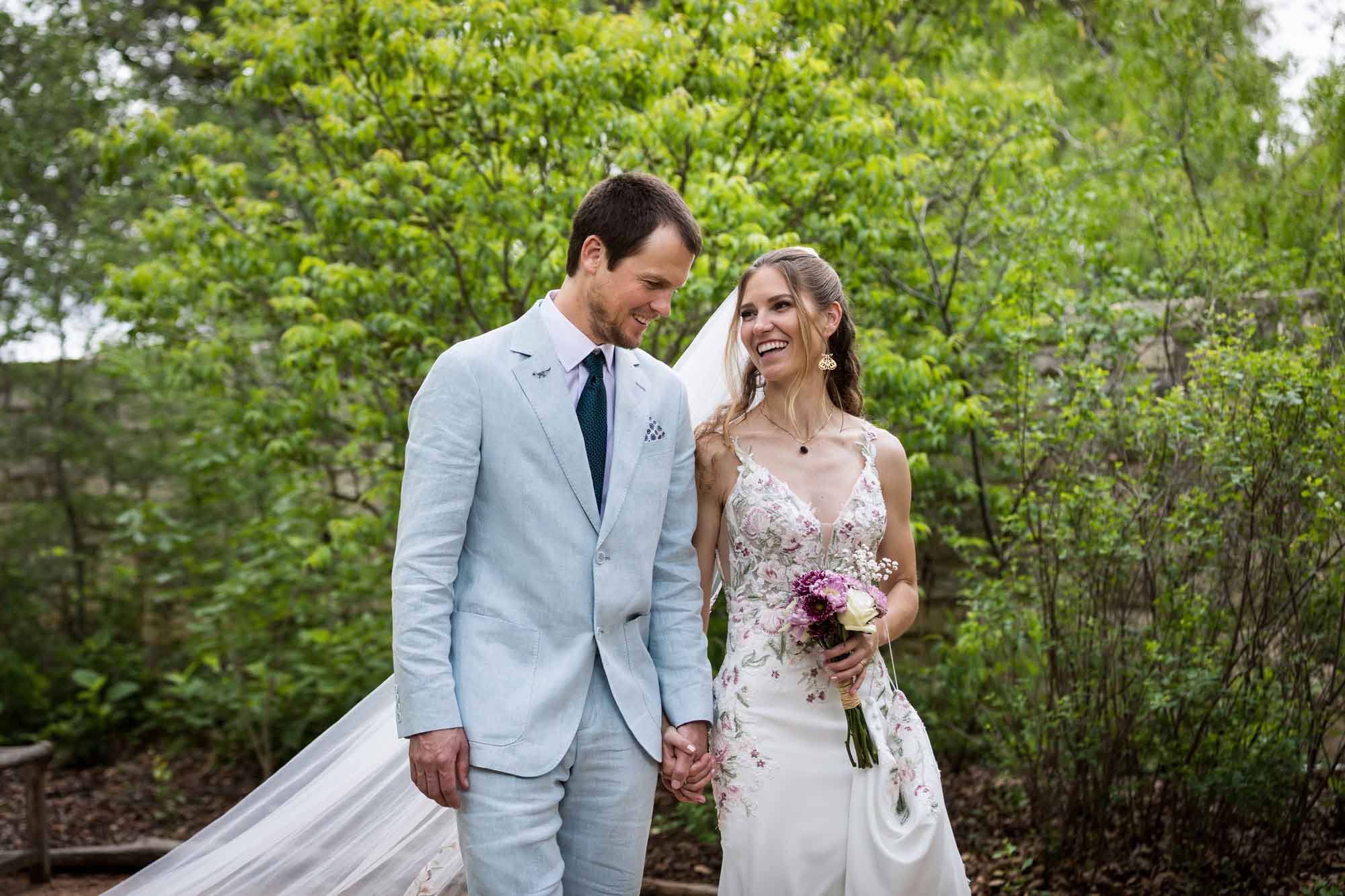 Lady Bird Johnson Wildflower Center wedding photos of a bride and groom walking hand in hand in woodland gardens