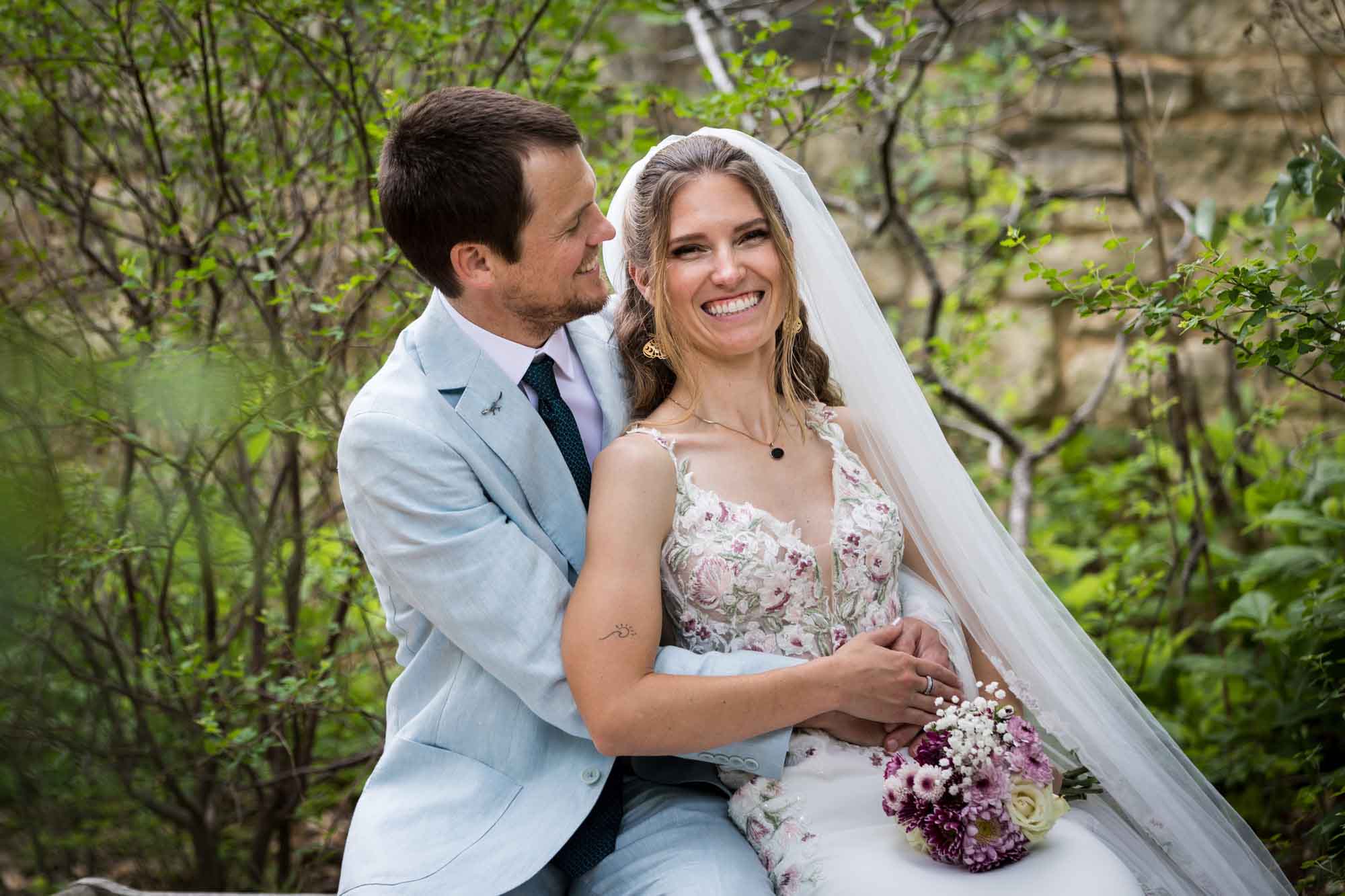 Lady Bird Johnson Wildflower Center wedding photos of a bride and groom sitting on bench laughing
