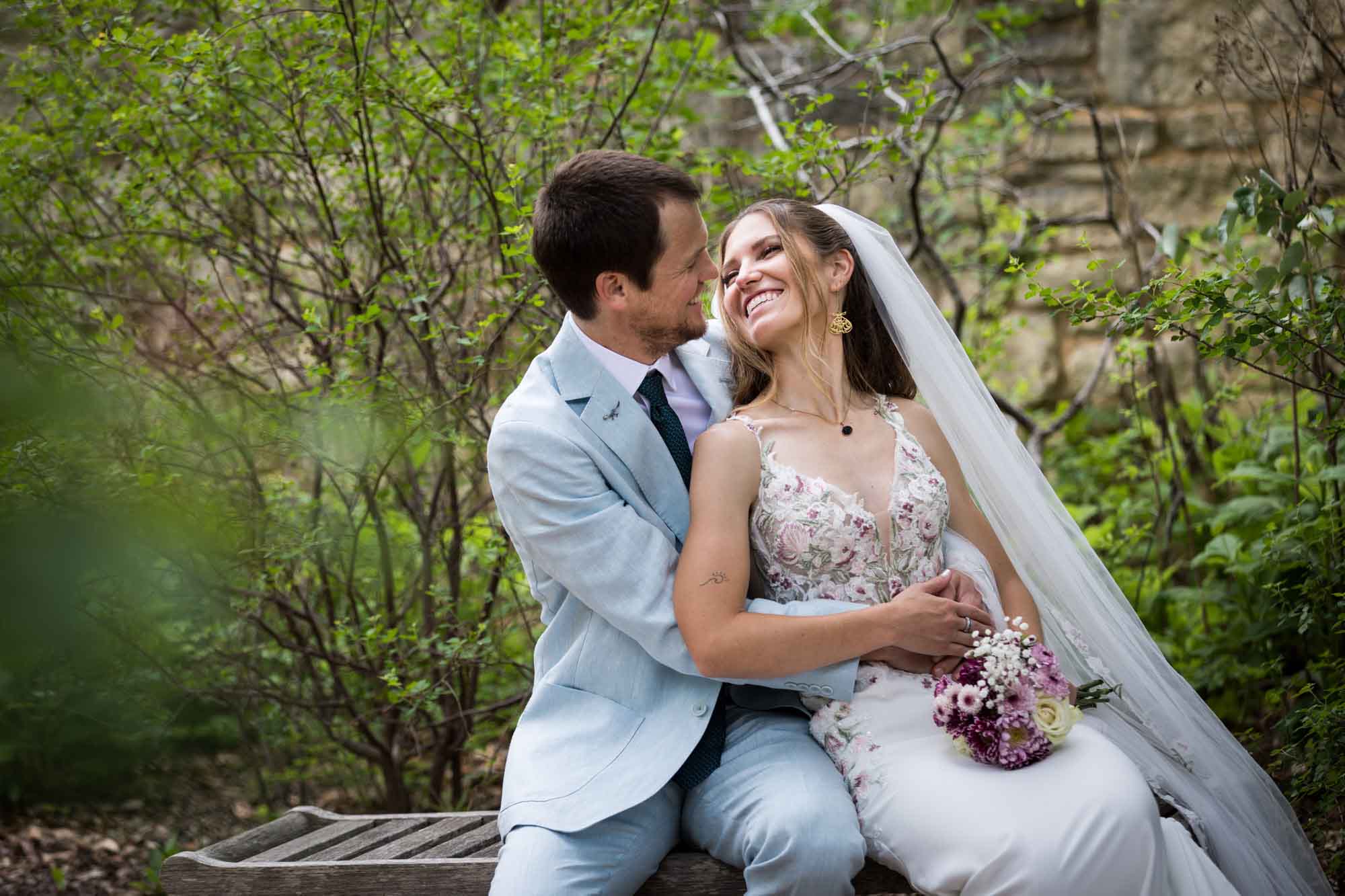 Lady Bird Johnson Wildflower Center wedding photos of a bride and groom sitting on bench laughing