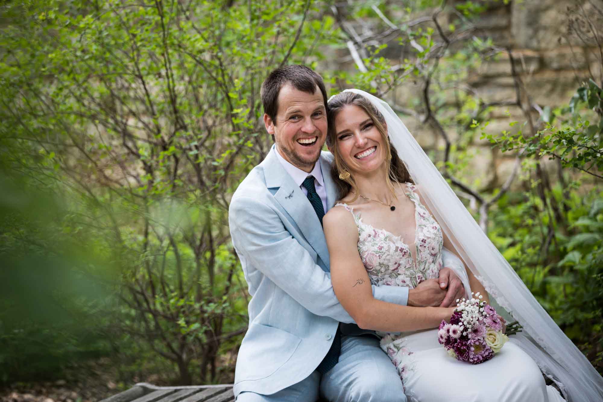 Lady Bird Johnson Wildflower Center wedding photos of a bride and groom sitting on bench laughing