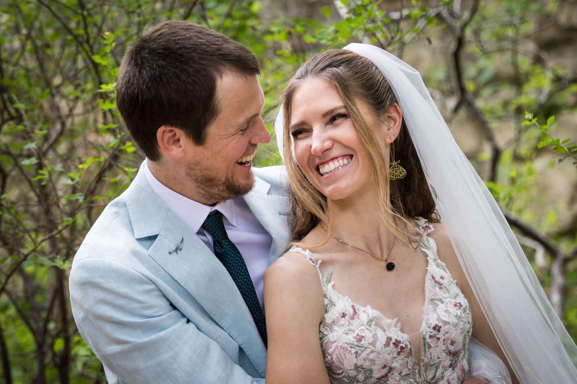 Lady Bird Johnson Wildflower Center wedding photos of a bride and groom sitting on bench laughing