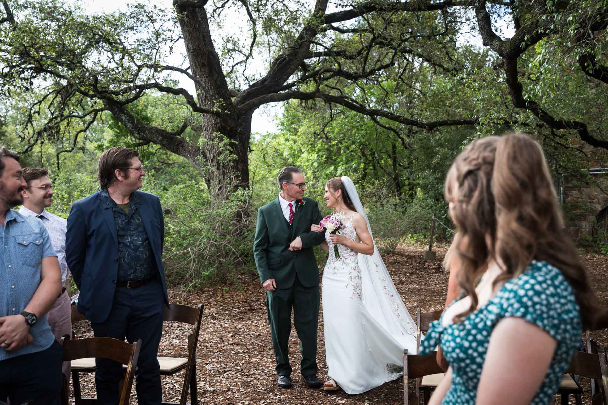 Bride looking at father in front of guests before she walks down aisle at ceremony during a Lady Bird Johnson Wildflower Center wedding
