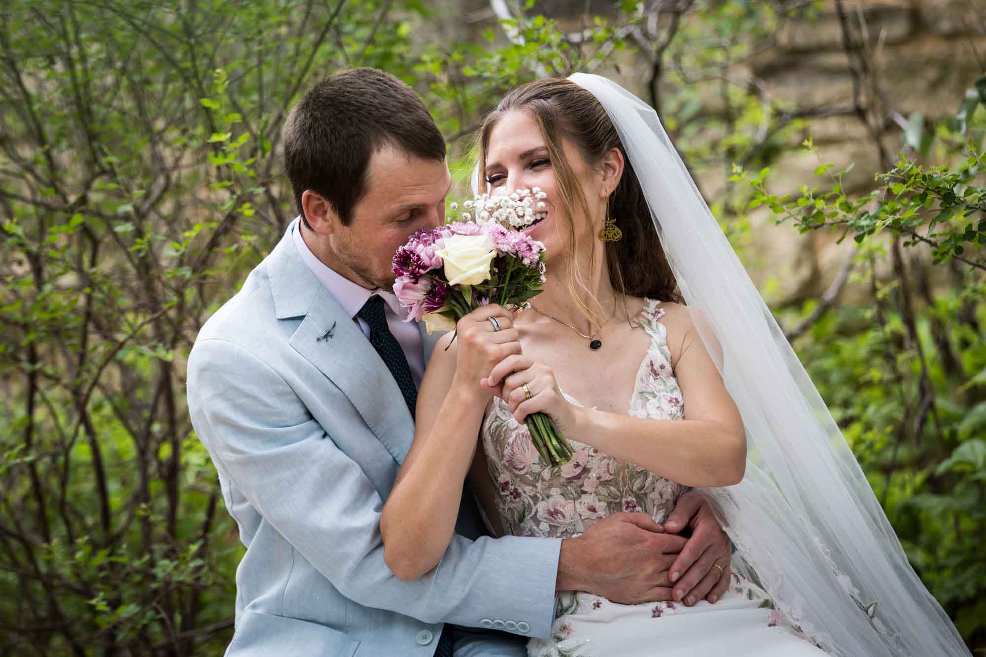 Lady Bird Johnson Wildflower Center wedding photos of a bride and groom sitting on bench laughing