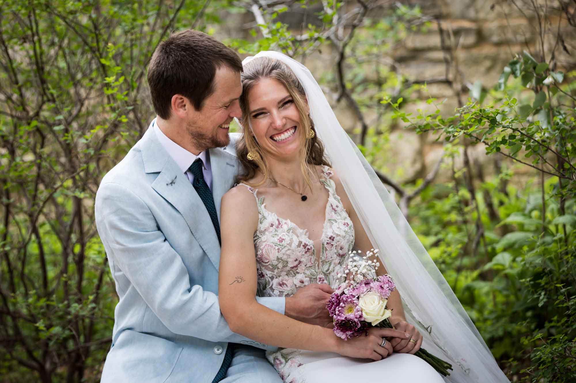 Lady Bird Johnson Wildflower Center wedding photos of a bride and groom sitting on bench laughing