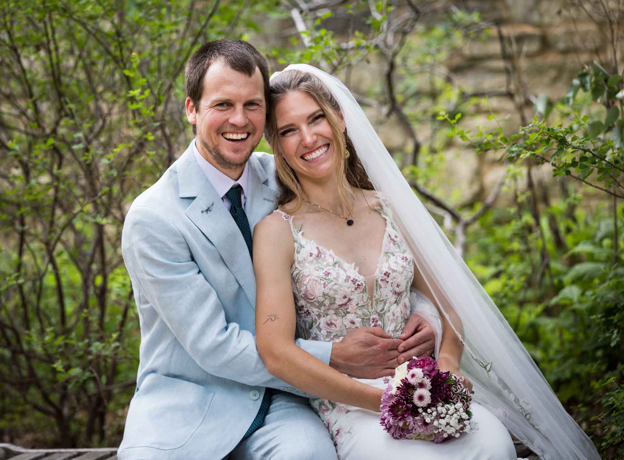 Lady Bird Johnson Wildflower Center wedding photos of a bride and groom sitting on bench laughing