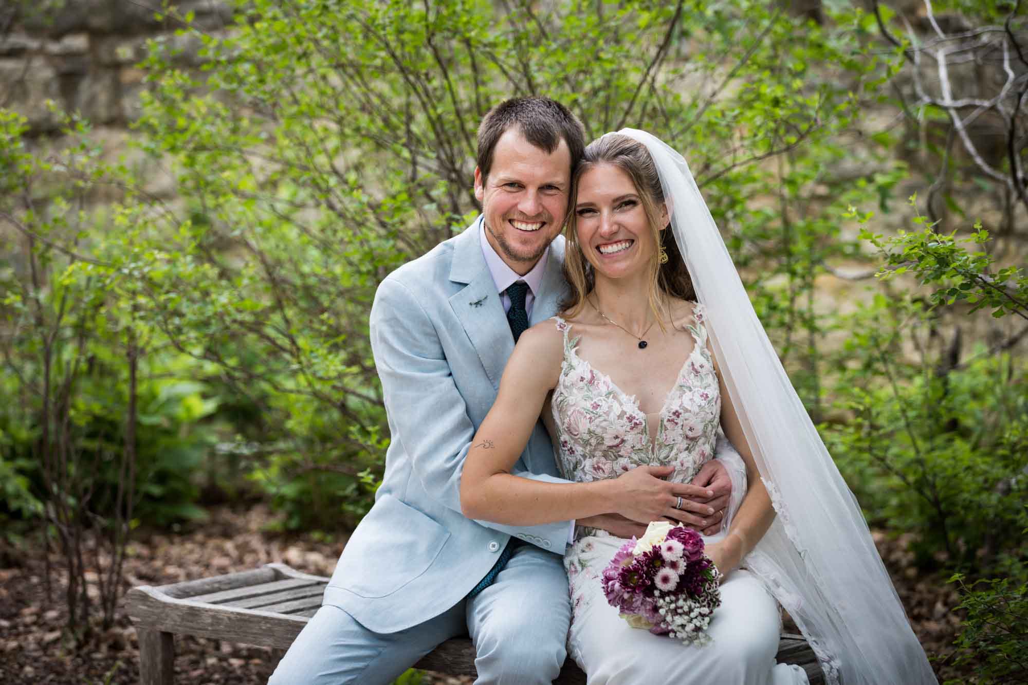 Lady Bird Johnson Wildflower Center wedding photos of a bride and groom sitting on bench laughing