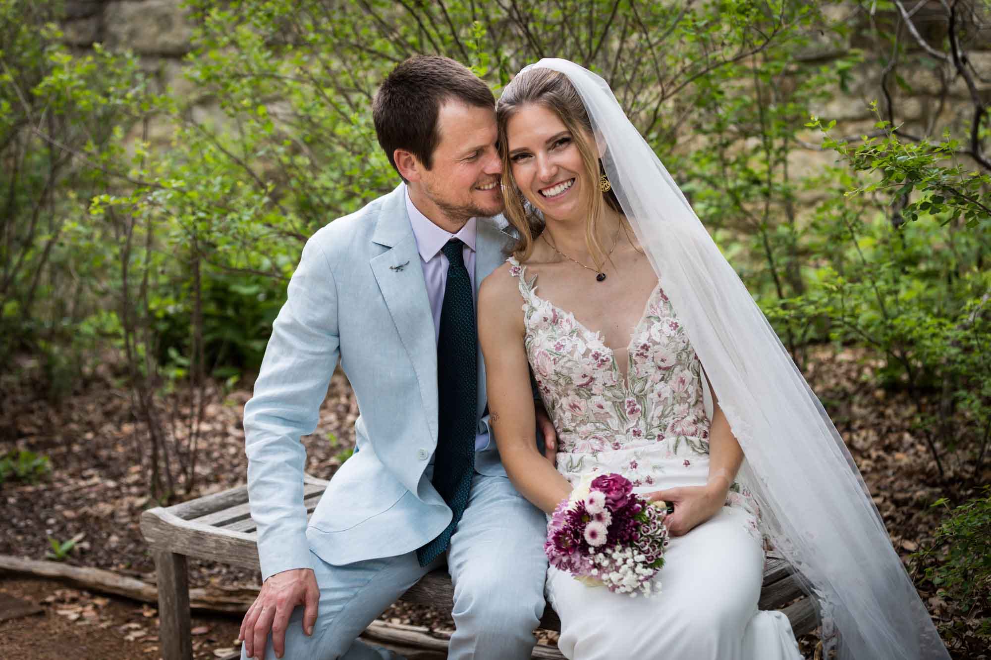 Lady Bird Johnson Wildflower Center wedding photos of a bride and groom sitting on bench laughing