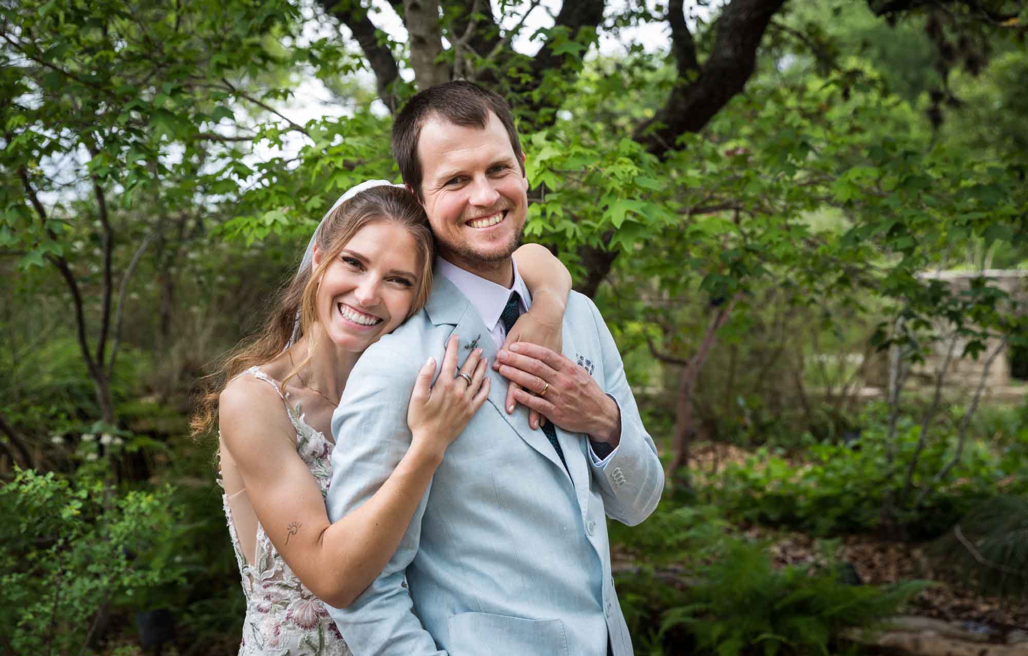 Lady Bird Johnson Wildflower Center wedding photos of a bride and groom standing in woodland gardens with bride's arms around groom