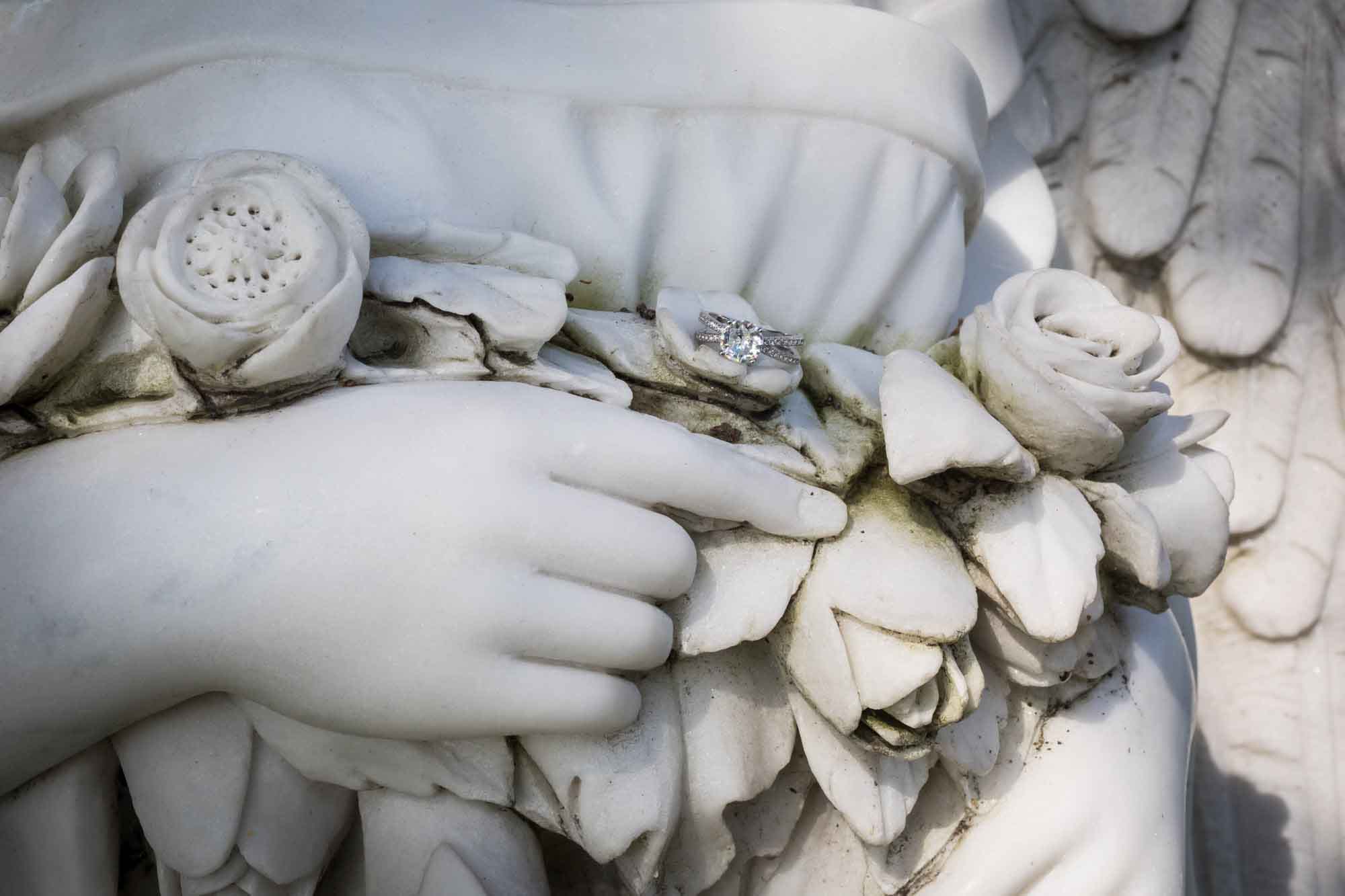 Hollywood Forever Cemetery engagement portrait of engagement ring sitting on stone angel sculpture