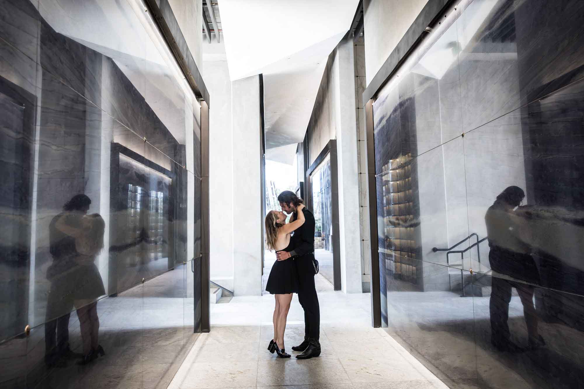 Man and woman hugging in hallway and reflected on shiny walls during a Hollywood Forever Cemetery engagement portrait session