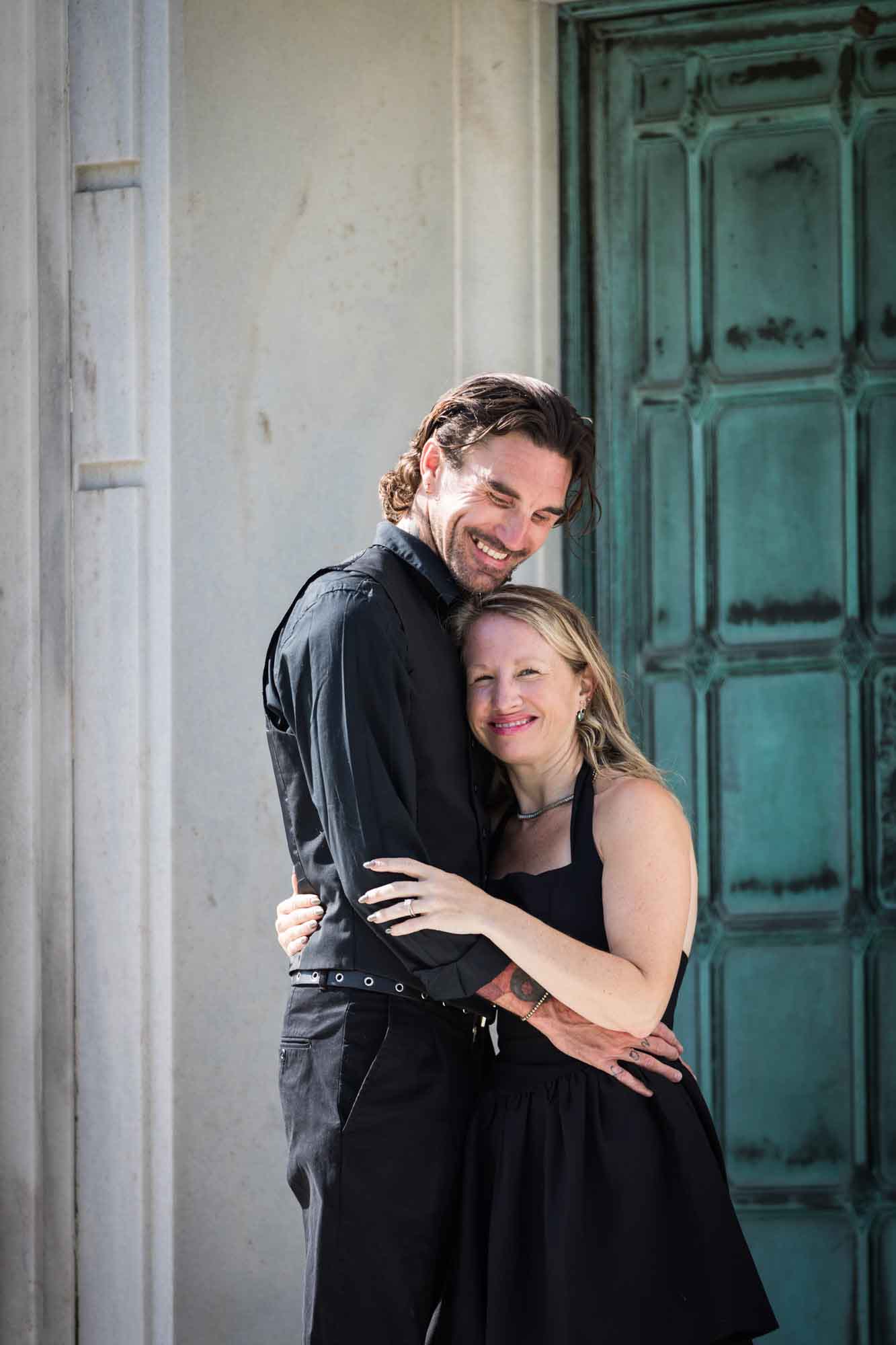 Hollywood Forever Cemetery engagement portrait of man and woman hugging in front of green door