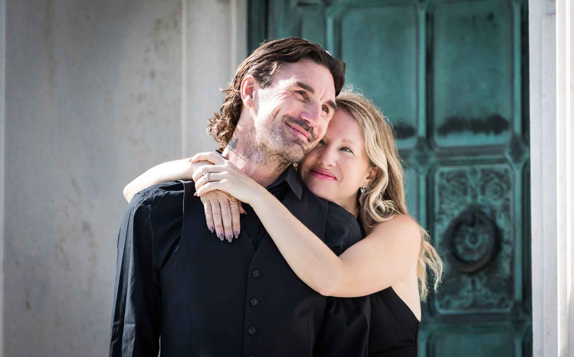 Hollywood Forever Cemetery engagement portrait of woman hugging man around the shoulders in front of green door