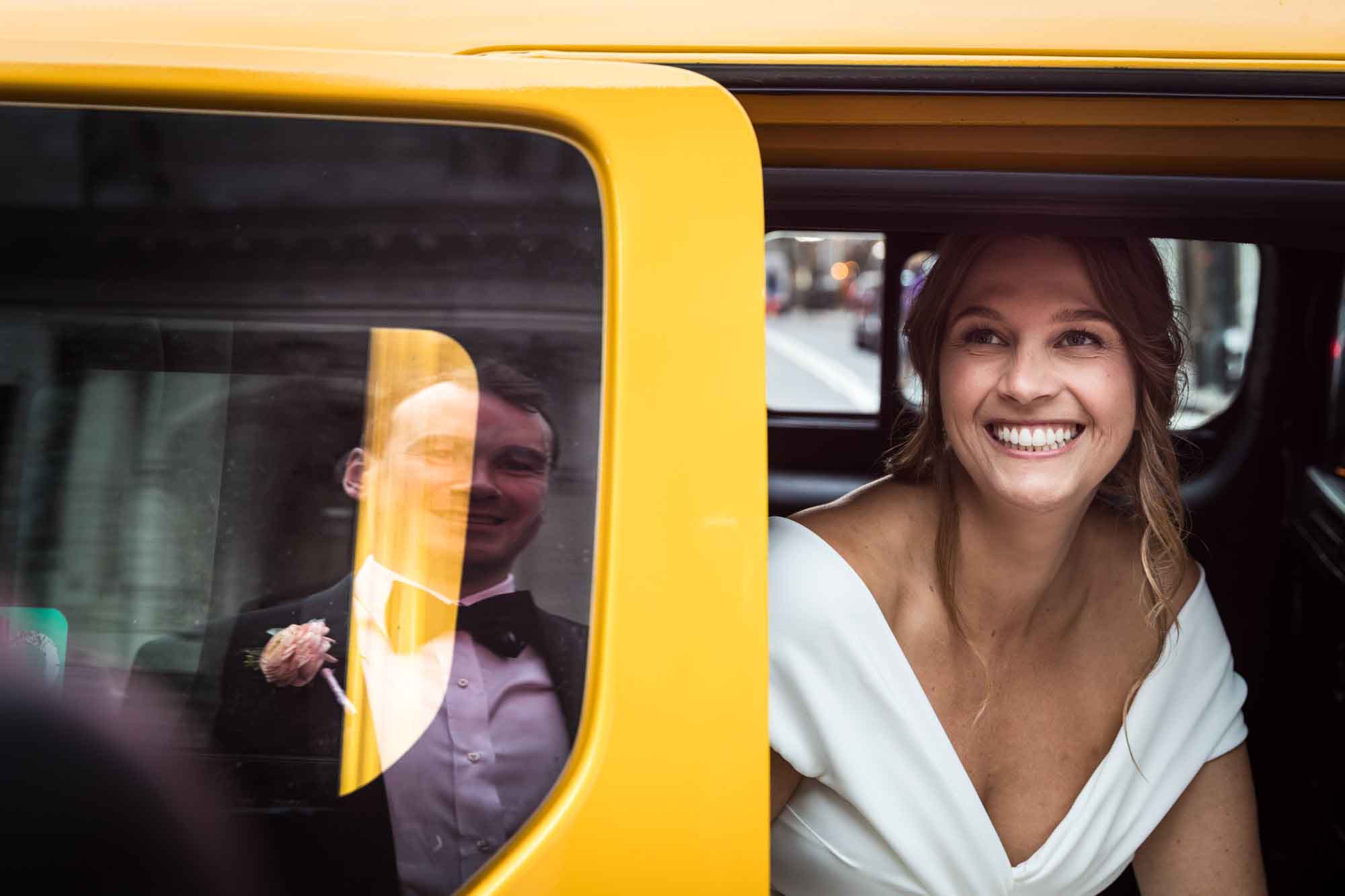 Bride sitting in yellow taxi smiling at groom reflected in window for an article on how to get a marriage license in Los Angeles
