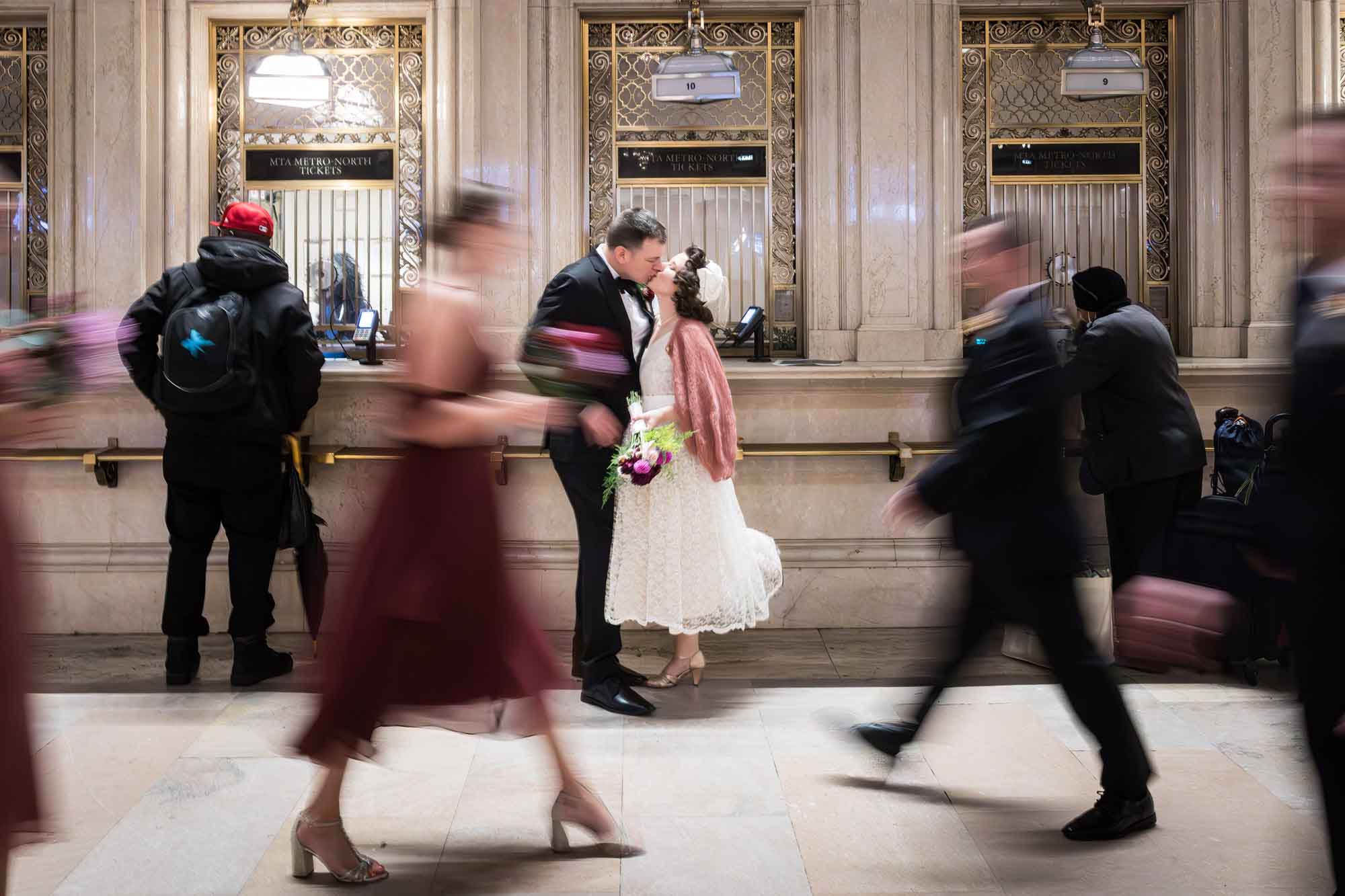 Bride and groom kissing in Grand Central with blur of people walking past for an article on how to get a marriage license in Los Angeles