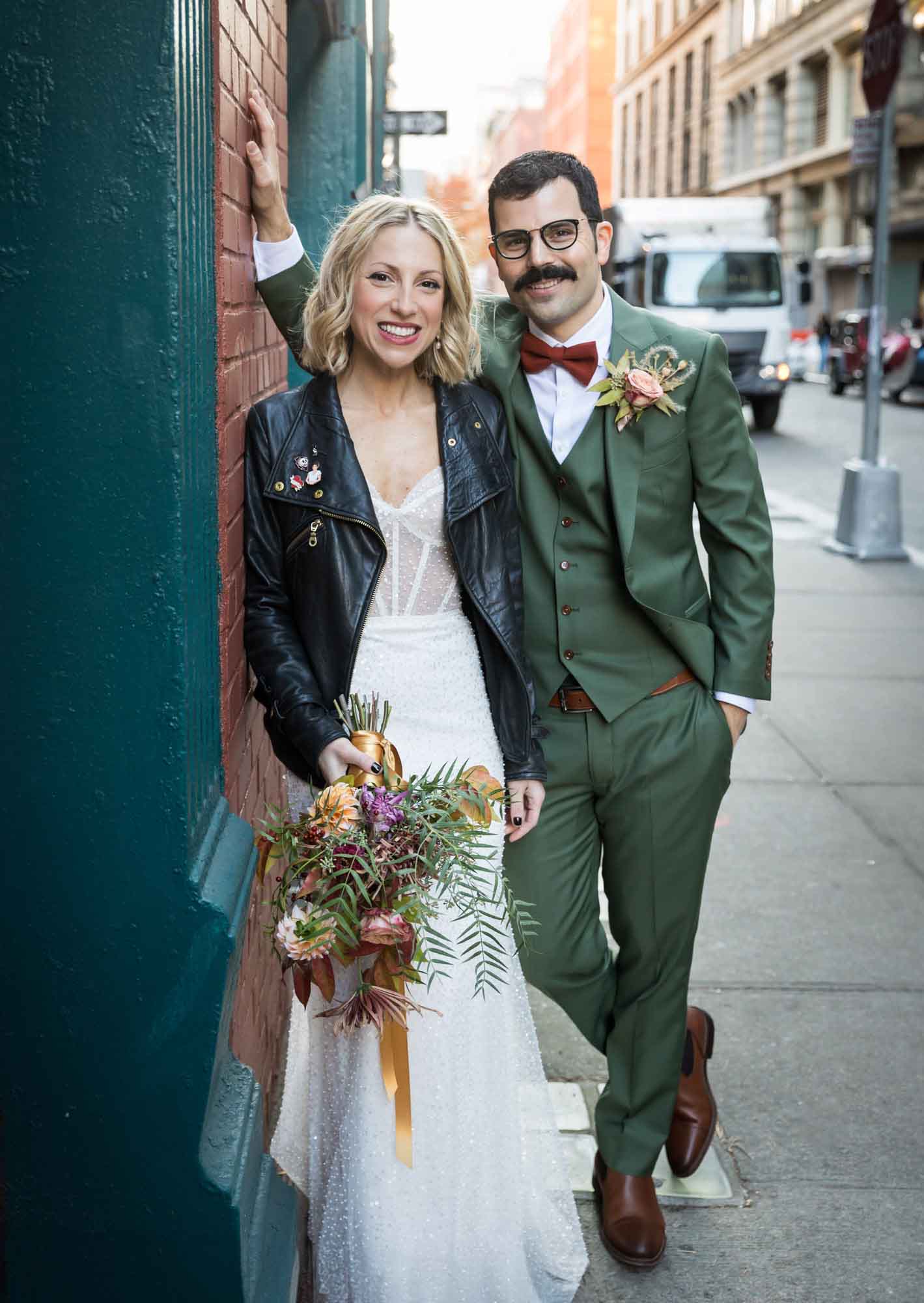Bride and groom standing together against green column on sidewalk for an article on how to get a marriage license in Los Angeles