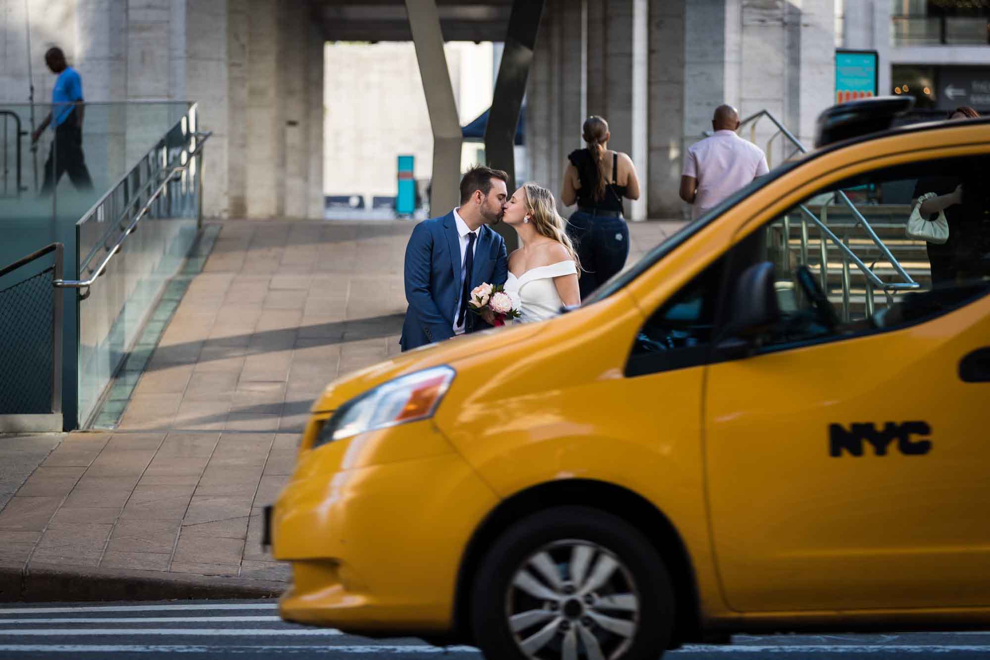 Bride and groom kissing behind yellow taxi for an article on how to get a marriage license in Los Angeles