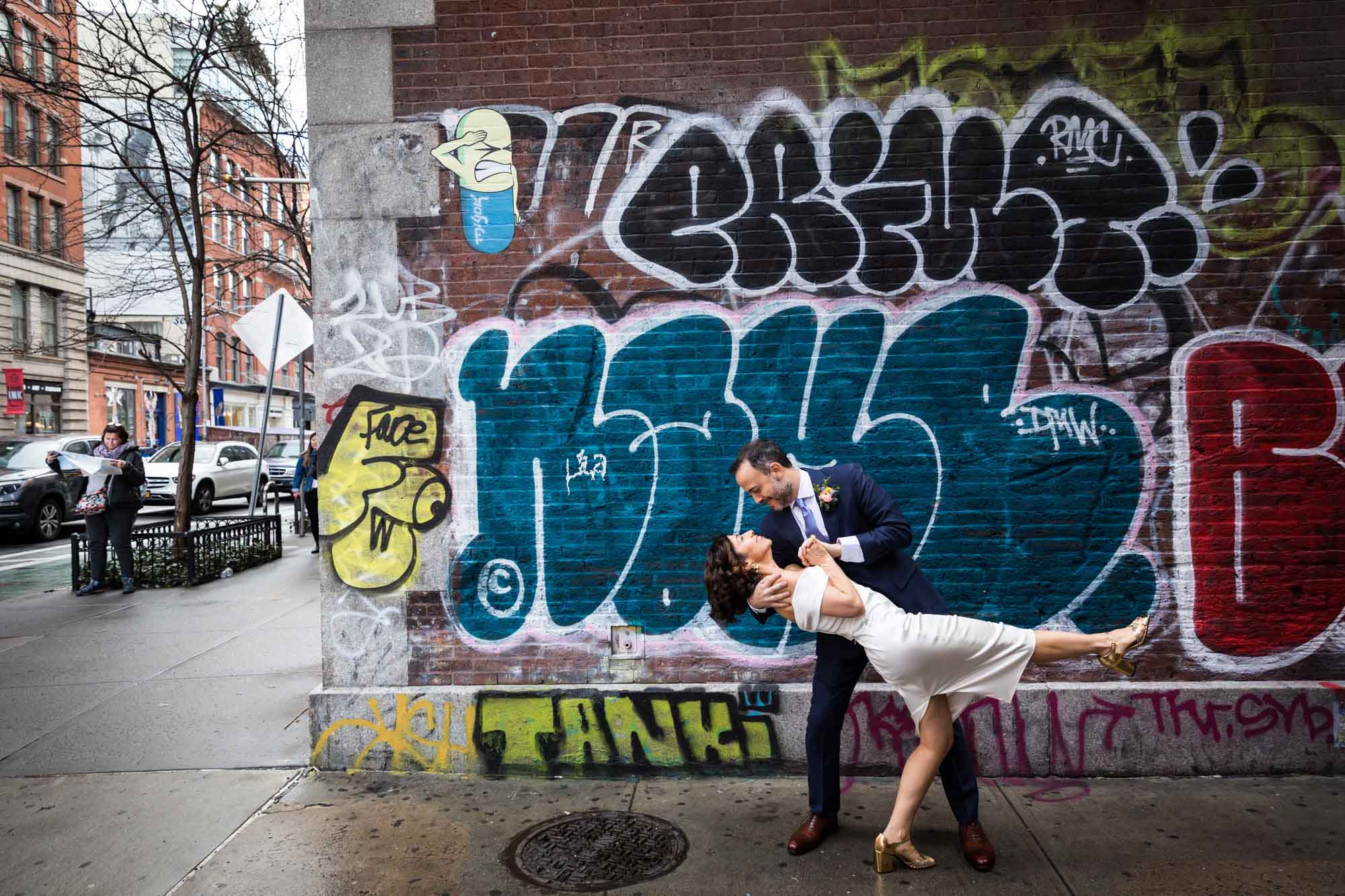 Bride and groom dancing on sidewalk with graffiti wall in background for an article on how to get a marriage license in Los Angeles