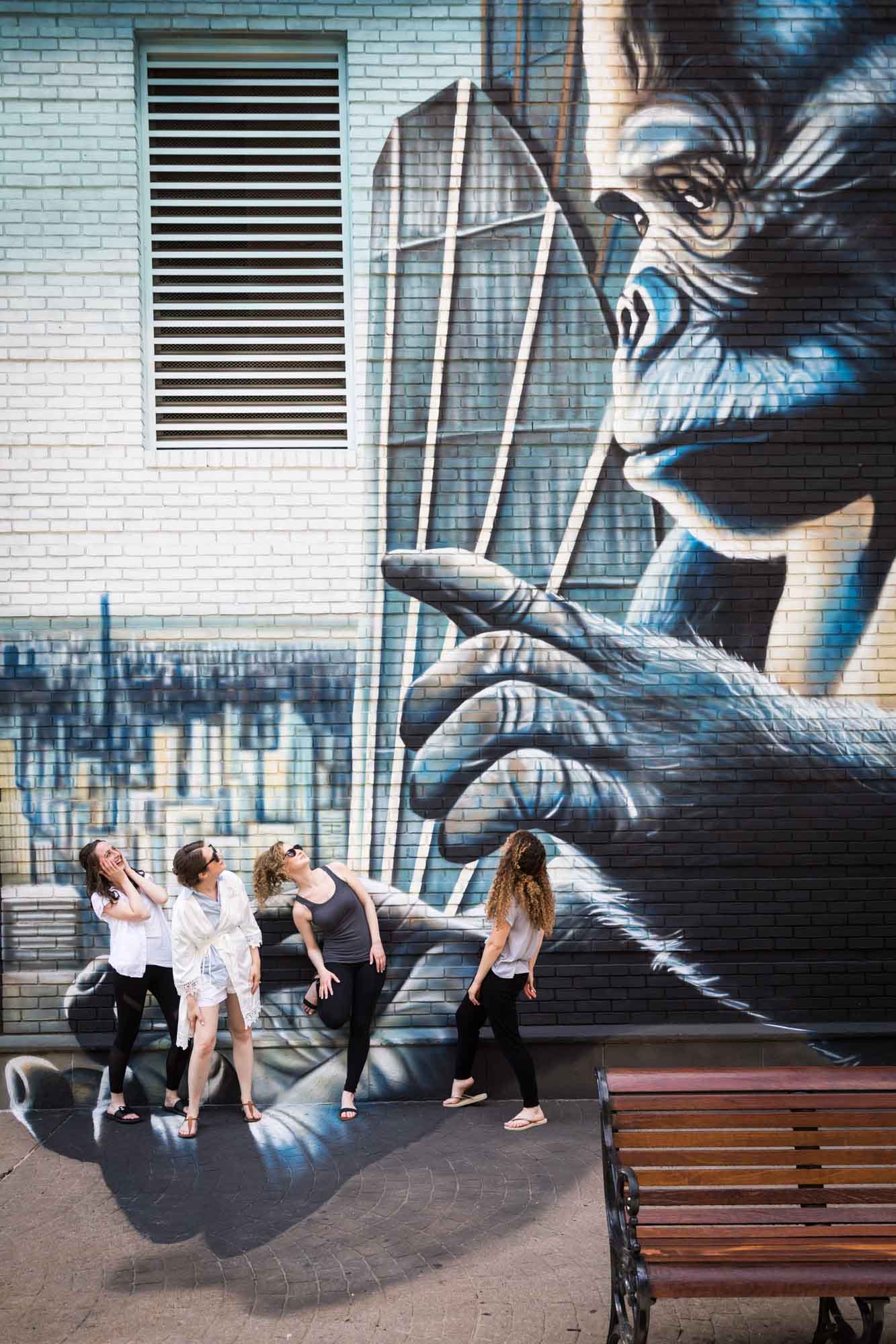 Four women looking back at mural showing large gorilla with hand outstretched for an article on how to get a marriage license in Los Angeles