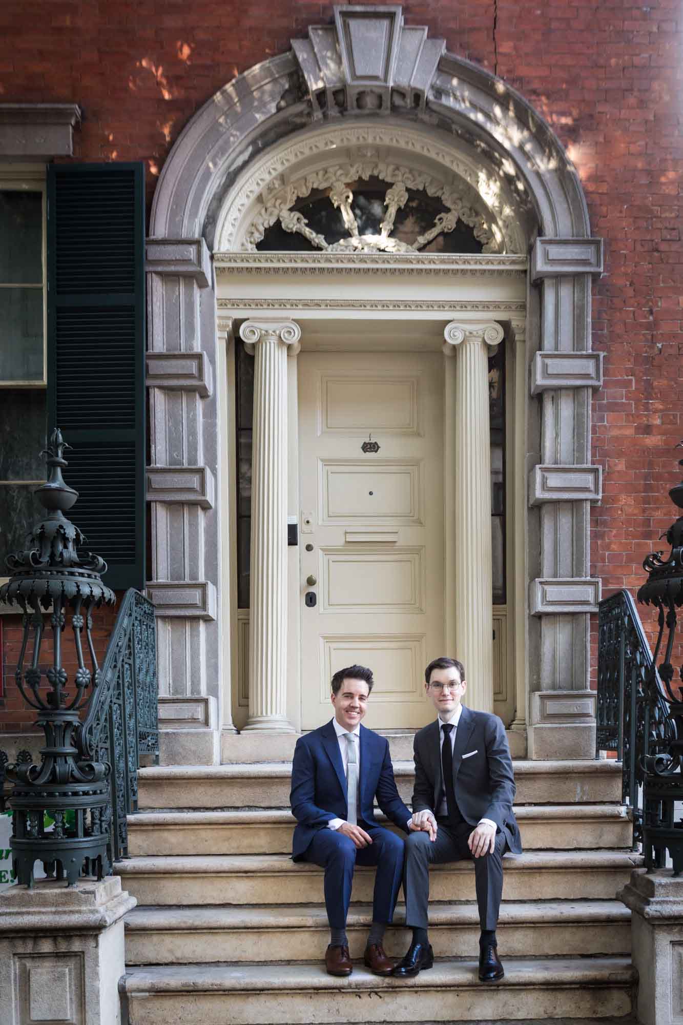 Two grooms sitting together on stairs in front of traditional Edwardian house for an article on how to get a marriage license in Los Angeles