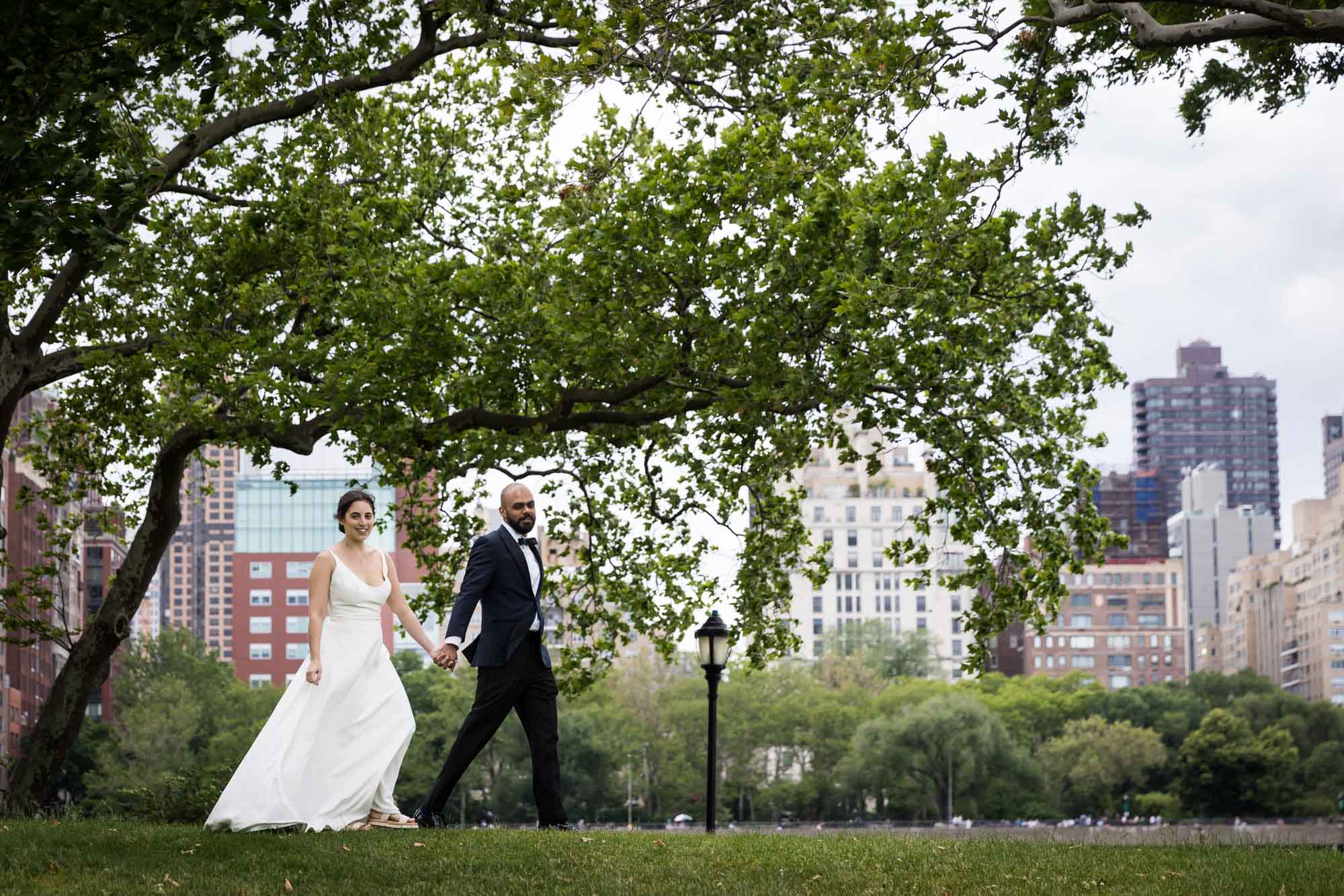 Bride and groom walking across park in Roosevelt Island for an article on how to get a marriage license in Los Angeles