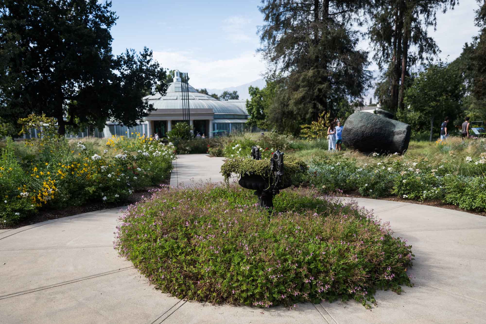 Circular sidewalk surrounded by wildflower beds in front of Conservatory of Botanical Science for a Huntington Gardens photo shoot guide article