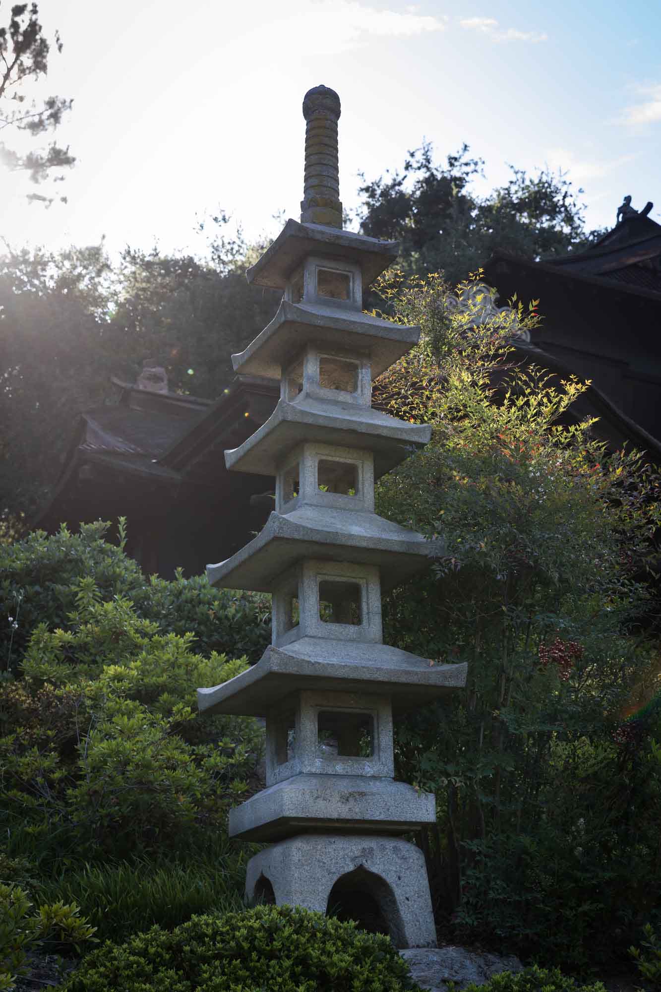 Tall pagoda in front of trees and Japanese wooden building in Japanese Garden for a Huntington Gardens photo shoot guide article