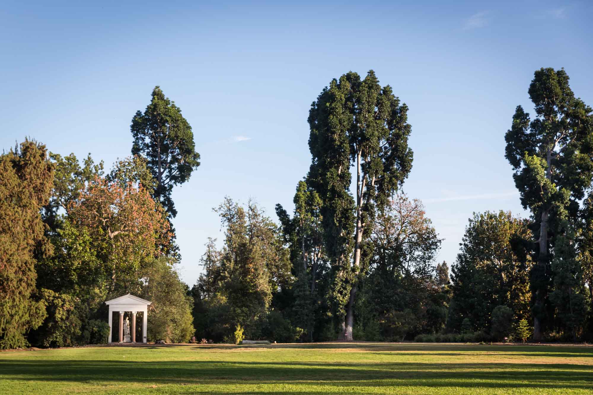 Large open lawn with trees and stone architectural sculpture in the background for a Huntington Gardens photo shoot guide article