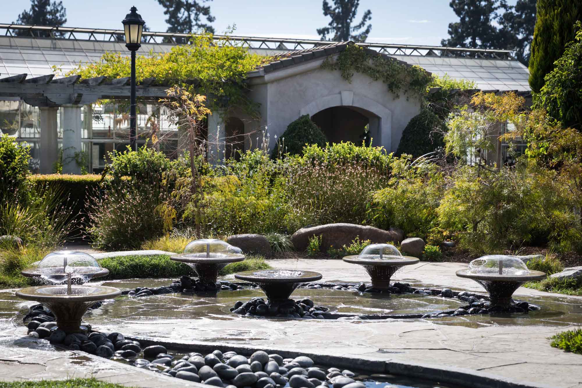 Low fountains with water flowing in front of plants and stone building in the Children's Garden for a Huntington Gardens photo shoot guide article