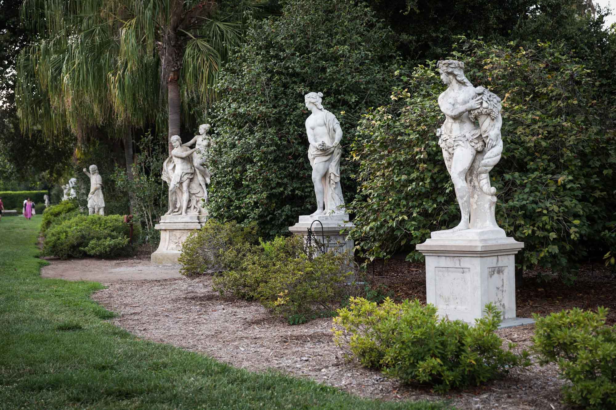 Rows of classical stone sculptures in the North Vista sculpture garden in front of bushes for a Huntington Gardens photo shoot guide article