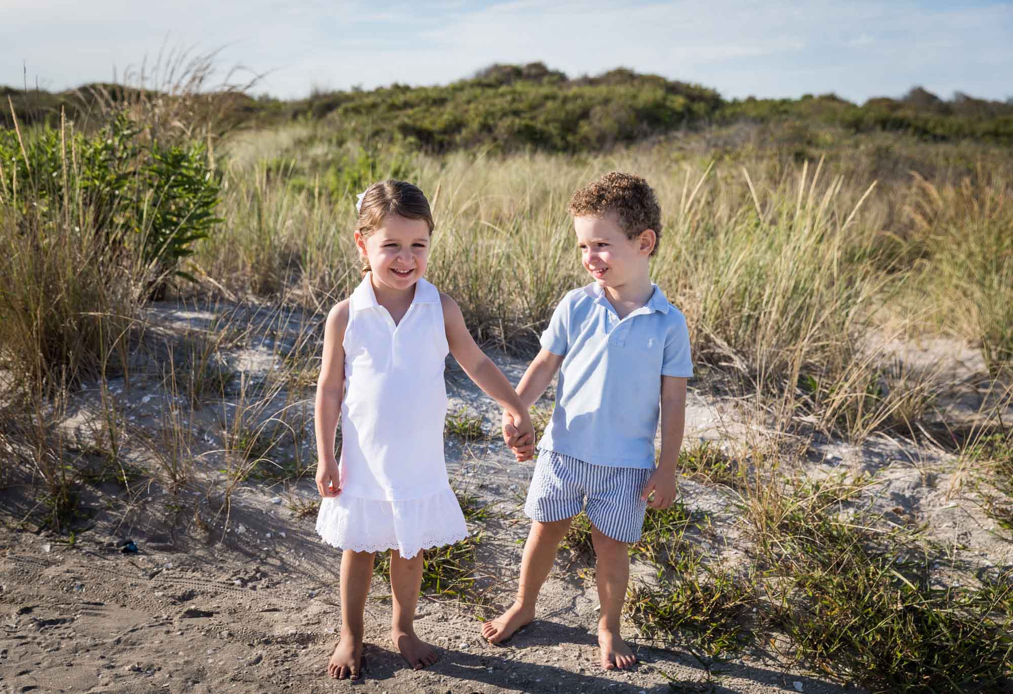 Little boy and girl holding hands in front of sea grass for an article on La Jolla Cove family photos