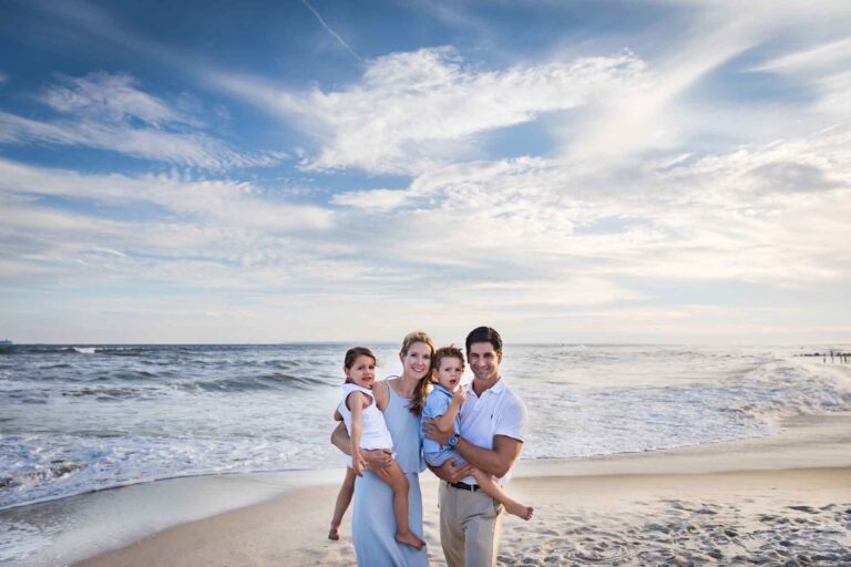 Mother and father holding two children in front of beach for an article on La Jolla Cove family photos