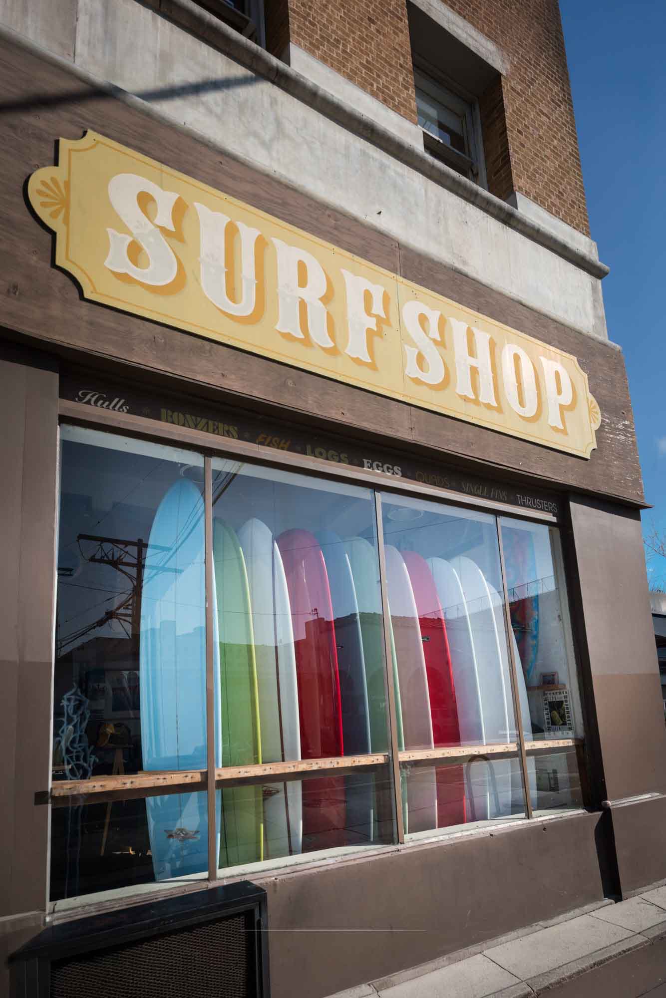 Mollusk Surf Shop window with large sign saying 'Surf Shop' and colorful surf boards in the window for an article on Venice Canals engagement photos