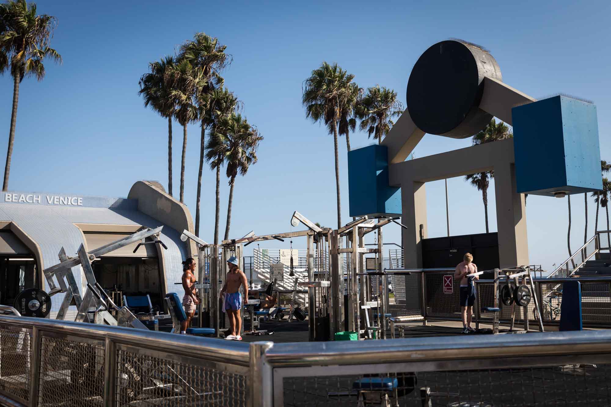 Muscle Beach weight pen with three shirtless men standing among weight machines for an article on Venice Canals engagement photos