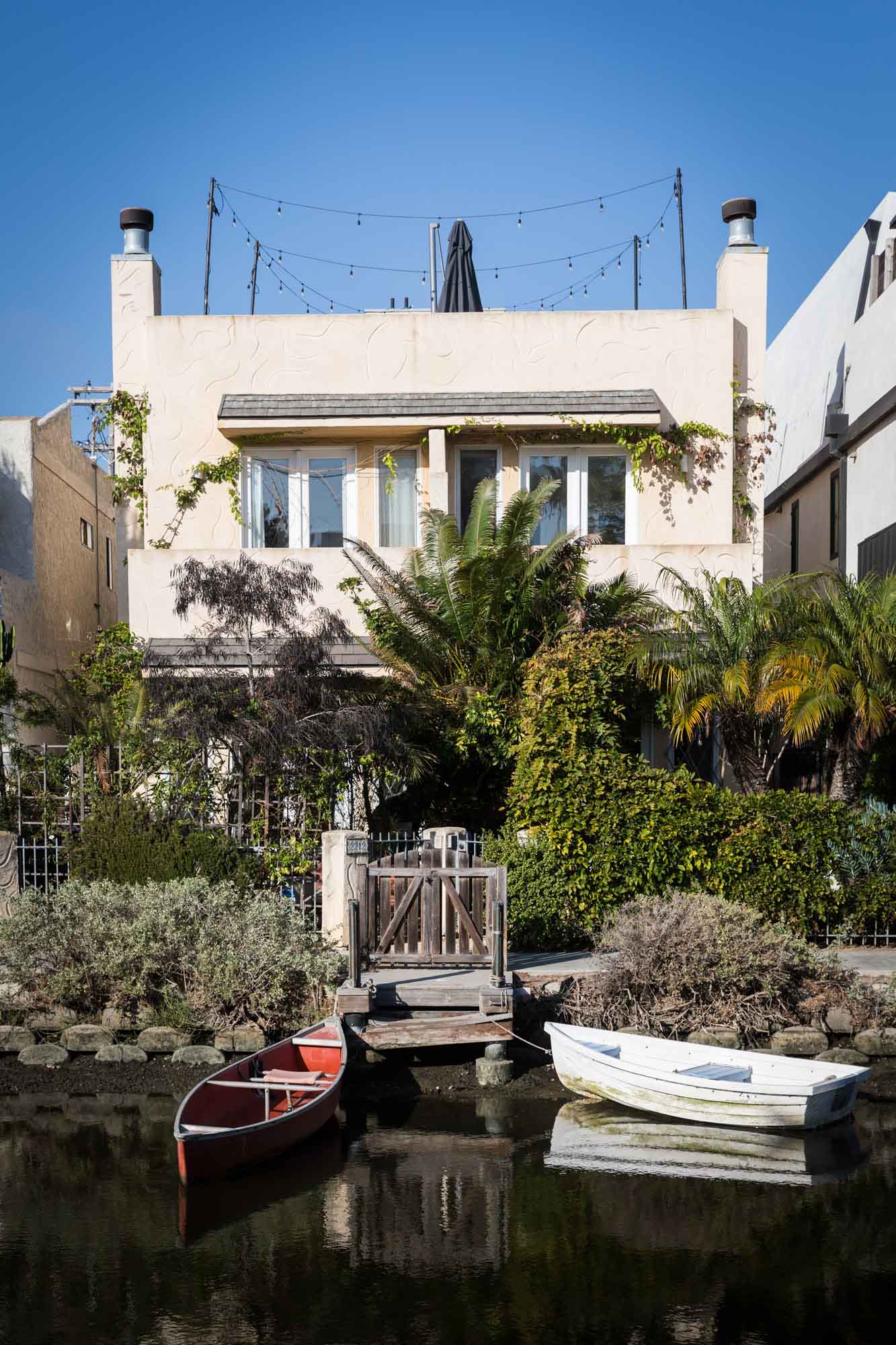 Modern home with long rectangular windows along Venice Canal with red and white rowboats in water for an article on Venice Canals engagement photos