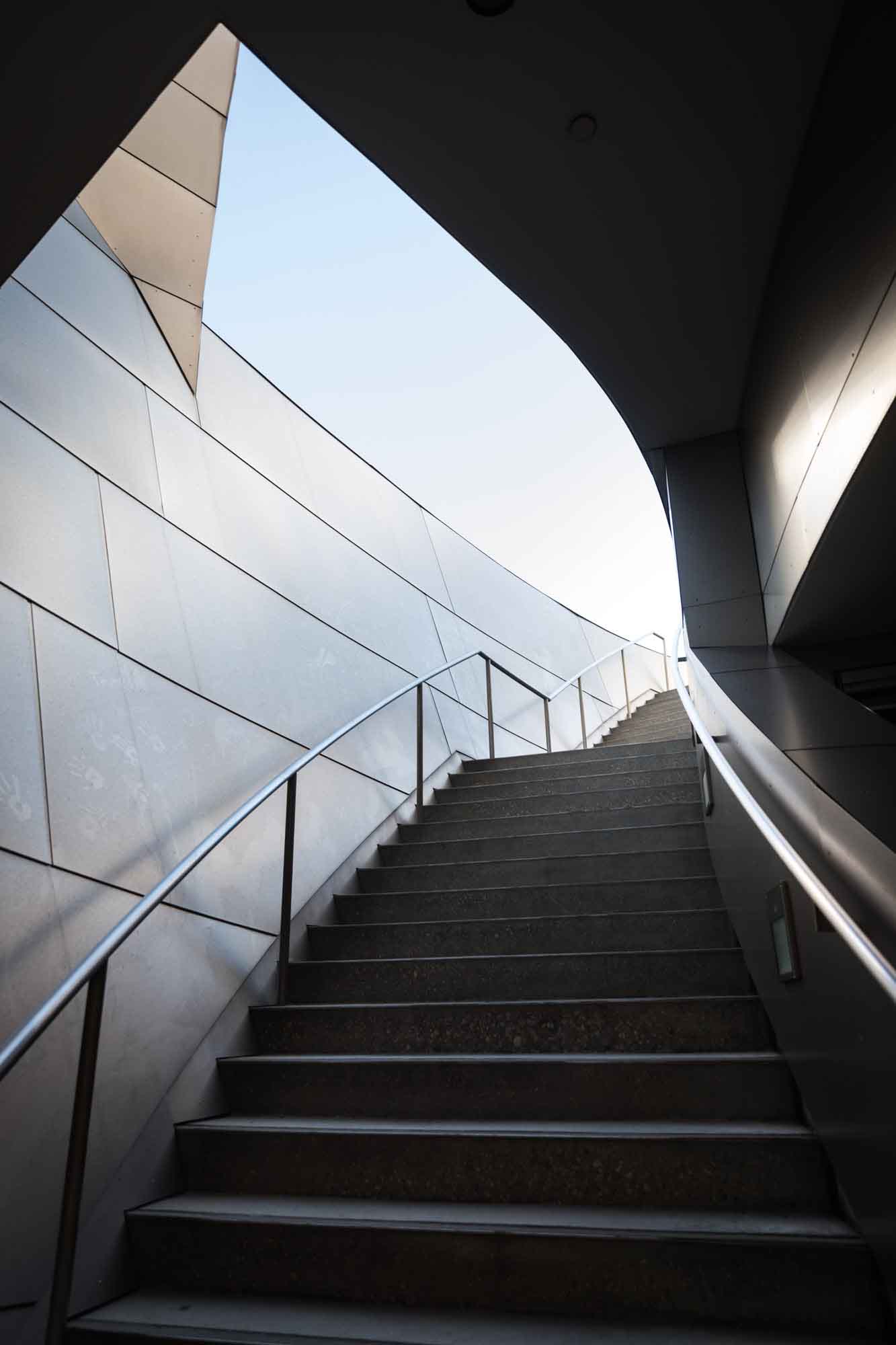 Darkly lit interior staircase with sky above leading to mezzanine level for an article on Walt Disney Concert Hall photos