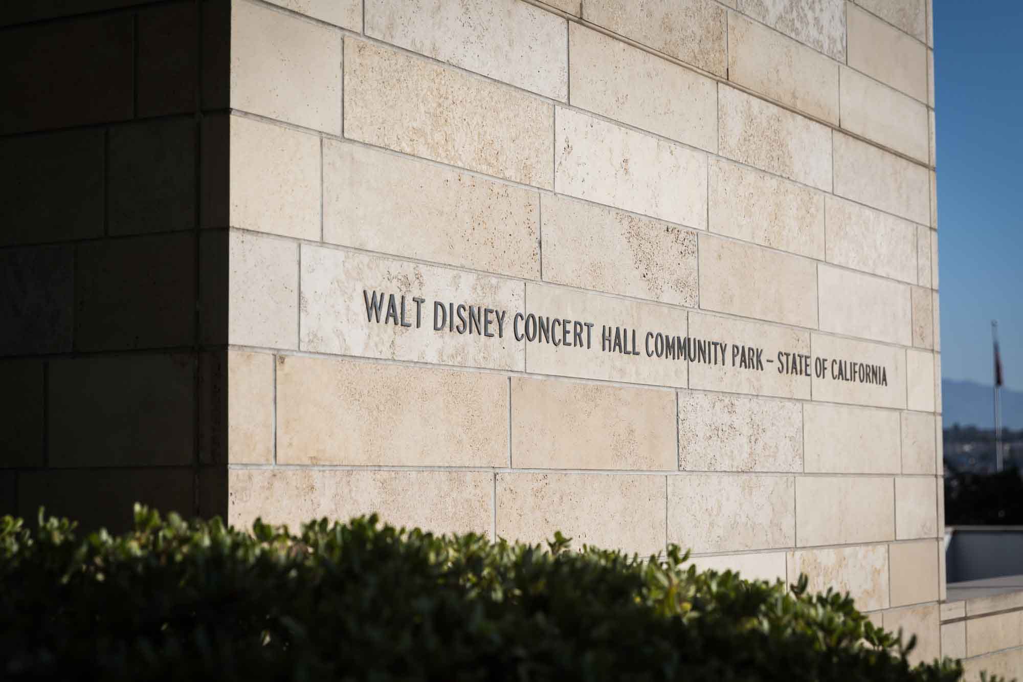 Sign saying 'Walt Disney Concert Hall Community Park - State of California' on beige brick wall for an article on Walt Disney Concert Hall photos