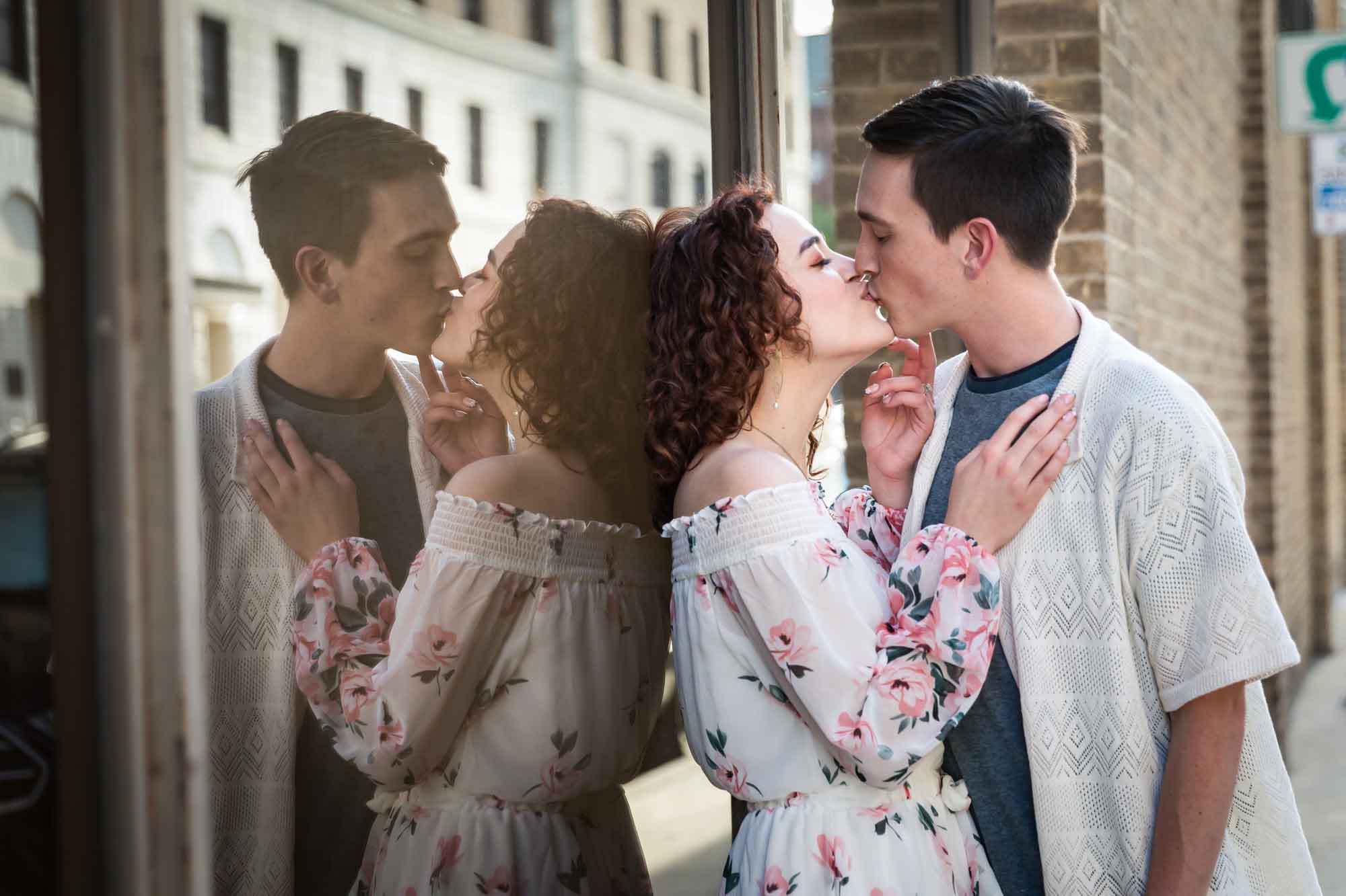 Man and woman kissing while leaning against reflective window with brick wall in background for an article on Walt Disney Concert Hall photos