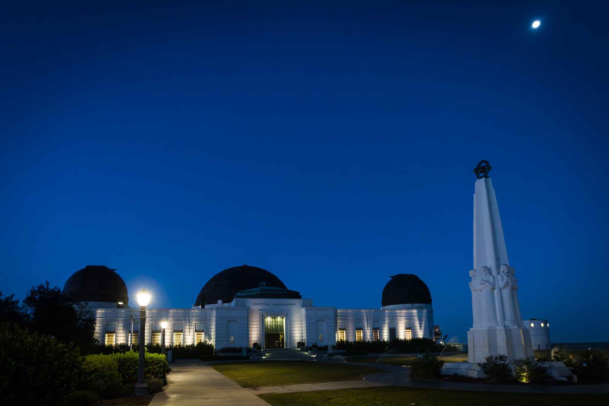 Griffith Observatory entrance and Astronomers Monument sculpture and moon before sunrise for an article on where to propose at the Griffith Observatory